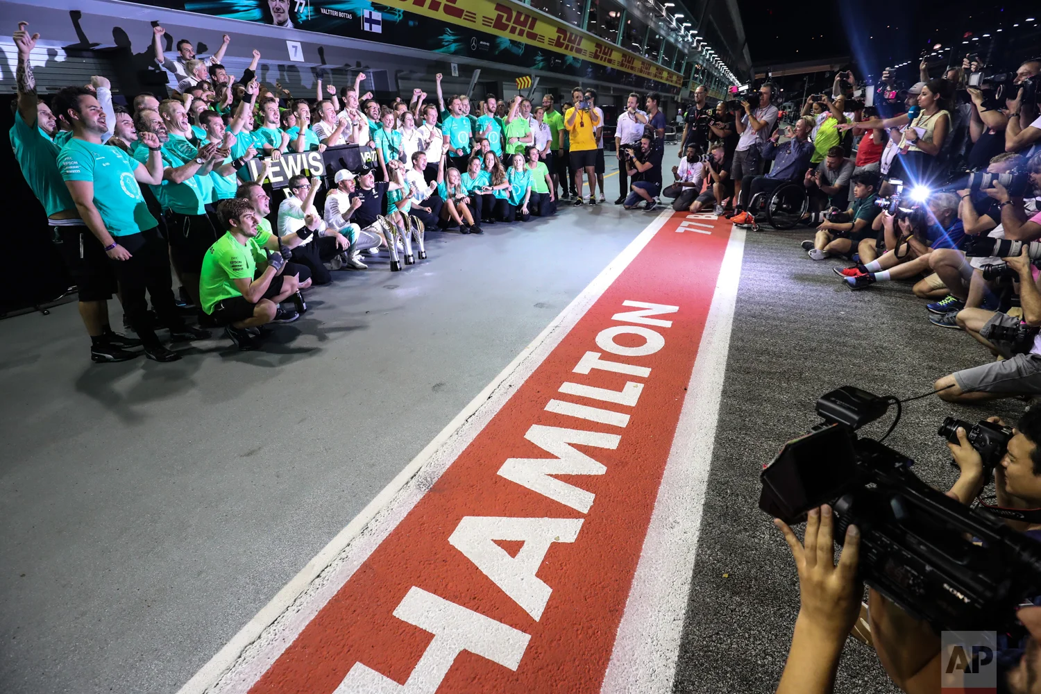 Mercedes driver Lewis Hamilton of Britain and Mercedes driver Valtteri Bottas of Finland celebrate with their team after the Singapore Formula One Grand Prix on the Marina Bay City Circuit Singapore, Sunday, Sept. 17, 2017. Hamilton won the race while Bottas finished third. (AP Photo/Yong Teck Lim)