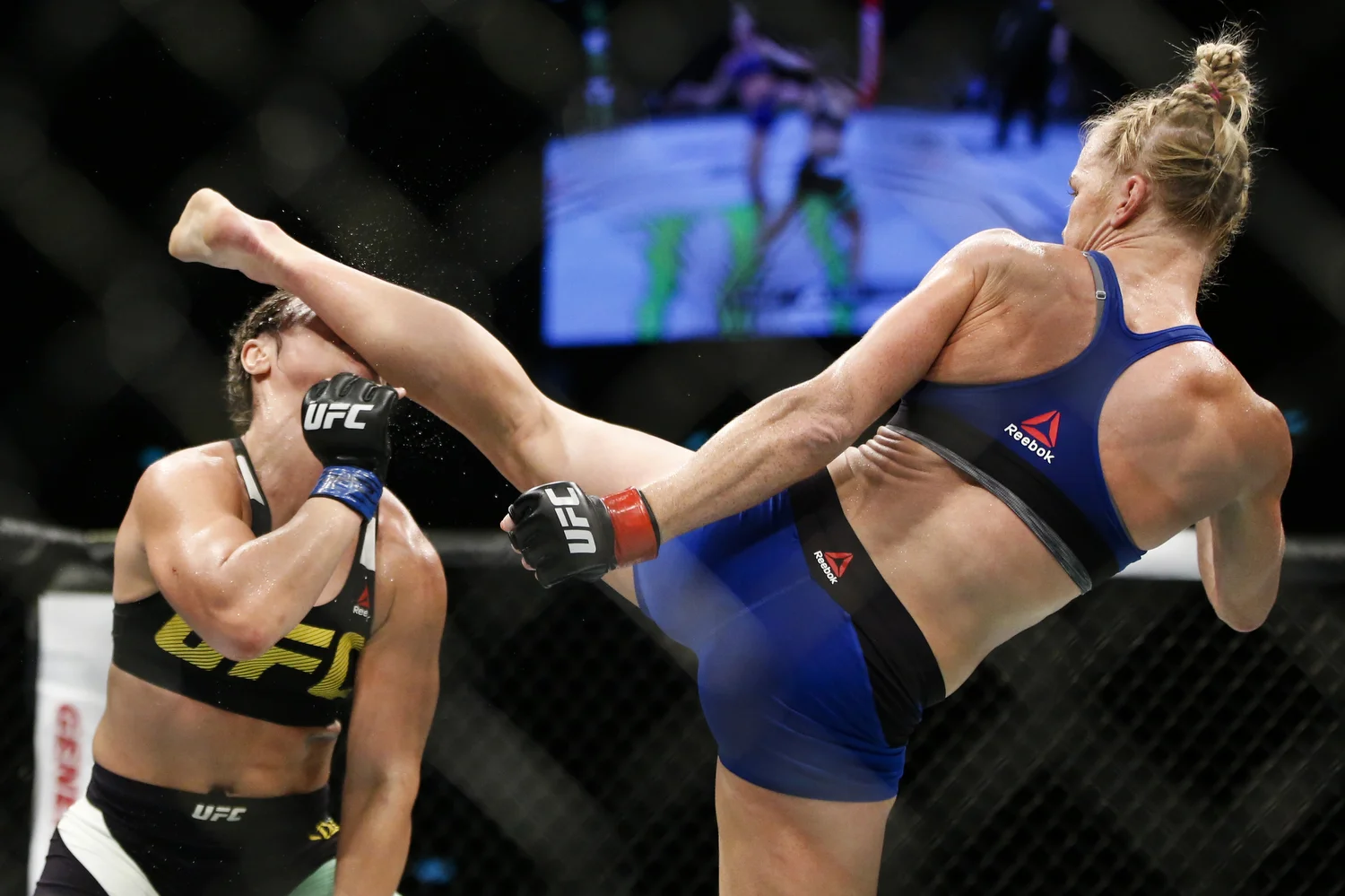 Holly Holm (R) of the United States knocks out Bethe Correia of Brazil with a kick during their bantamweight bout at the UFC Fight Night at the Singapore Indoor Stadium on June 17, 2017.