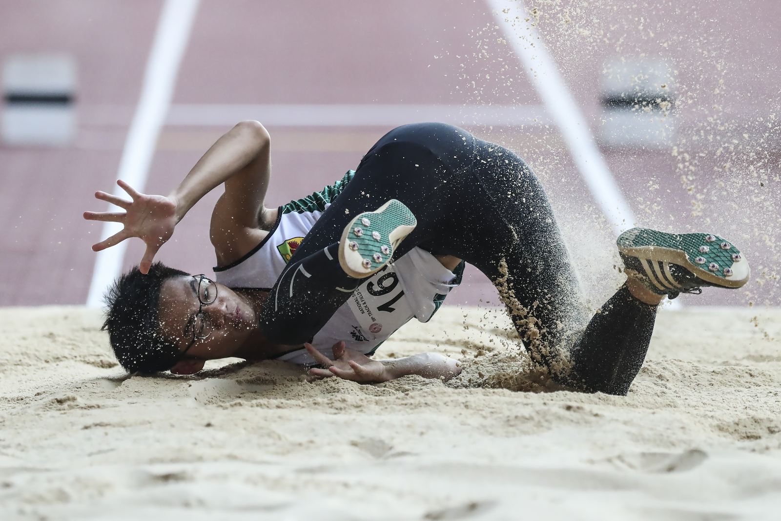 Ryan Lim of Raffles Institution falls on his attempt during the National Schools boys’ ‘A’ Division boys' triple jump final at the National Stadium on April 11, 2018 in Singapore. (Photo © Yong Teck Lim/Red Sports)