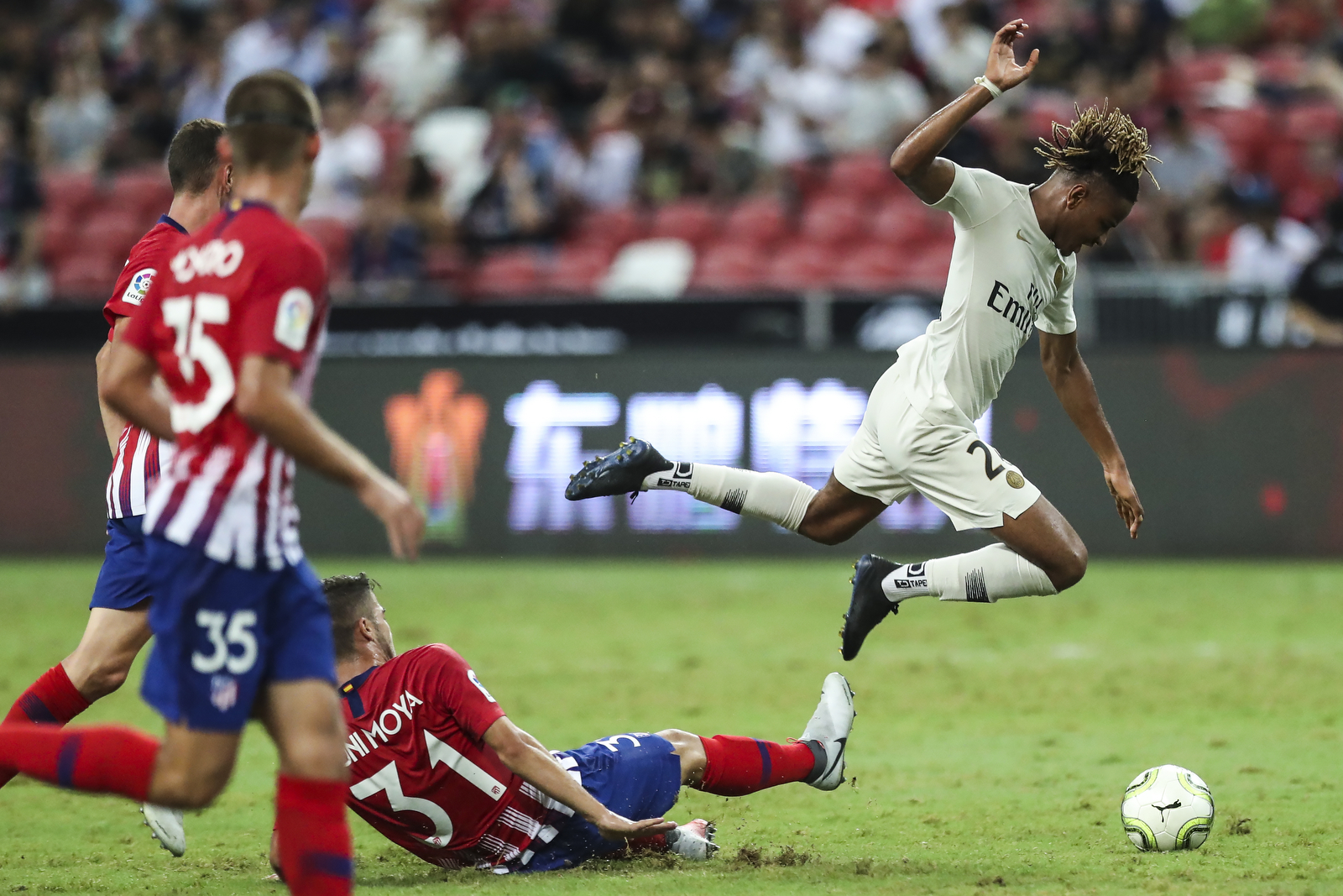  Paris Saint-Germain’s Christopher Nkunku jumps to avoid a tackle by Atletico Madrid’s Toni Moya during the International Champions Cup match between Paris Saint-Germain and Atletico Madrid in Singapore, Monday, July 30, 2018. (AP Photo/Yong Teck Lim