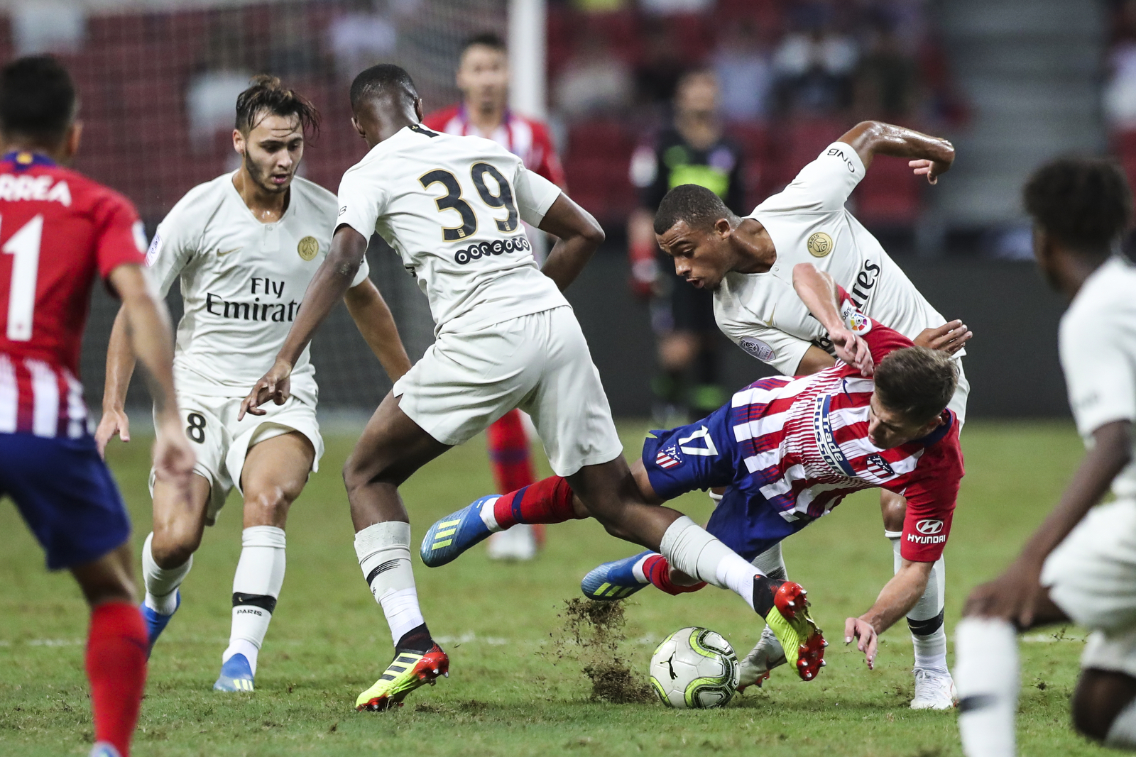  Atletico Madrid’s Luciano Vietto falls after a tackle by Paris Saint-Germain’s Antoine Bernede, right, and Moussa Sissako during the International Champions Cup match between Paris Saint-Germain and Atletico Madrid in Singapore, Monday, July 30, 201