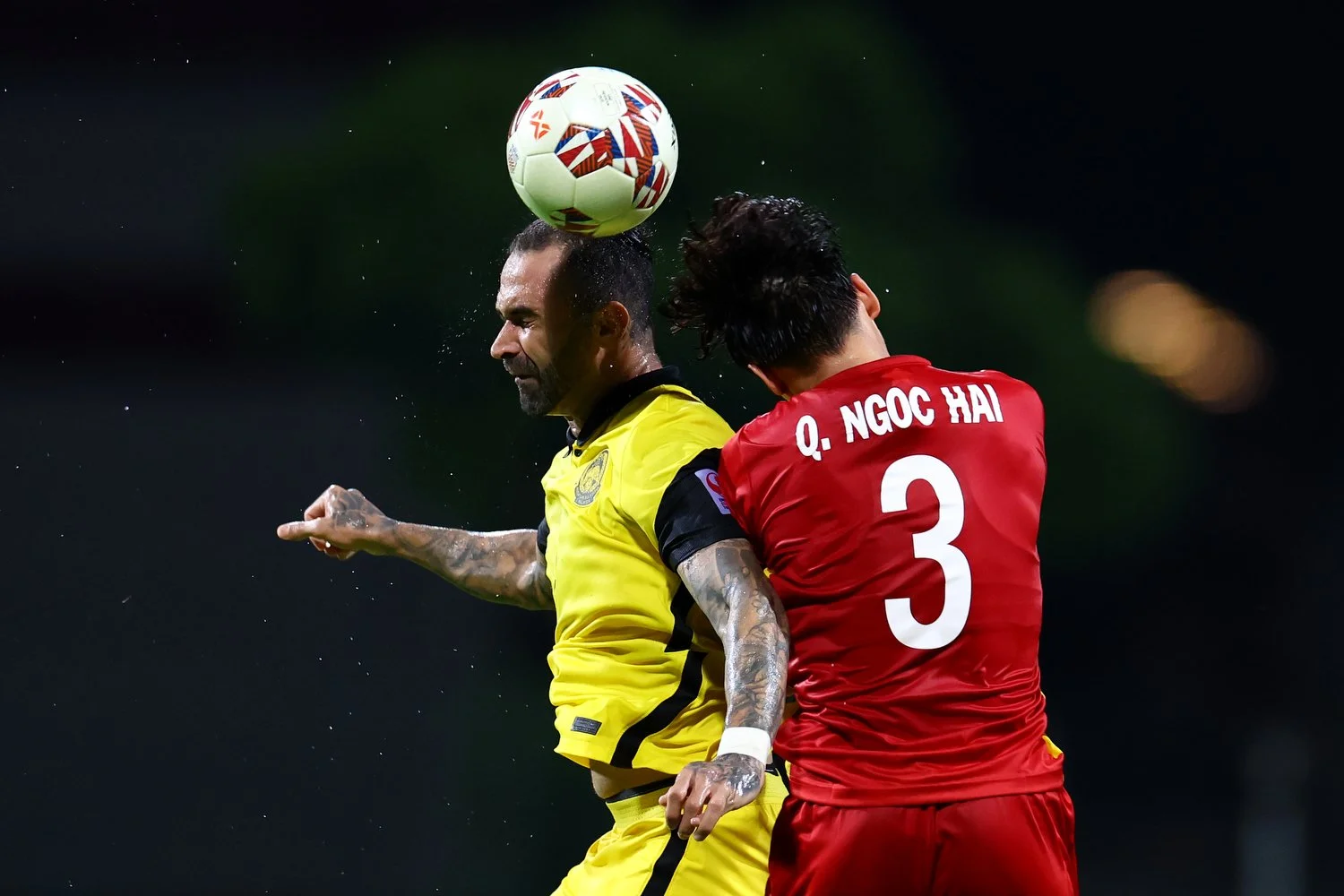  SINGAPORE, SINGAPORE - DECEMBER 12: Guilherme de Paula Lucrecio #9 of Malaysia heads the ball against Que Ngoc Hai #3 of Vietnam during the second half of their AFF Suzuki Cup Group B game at Bishan Stadium on December 12, 2021 in Singapore. (Photo 