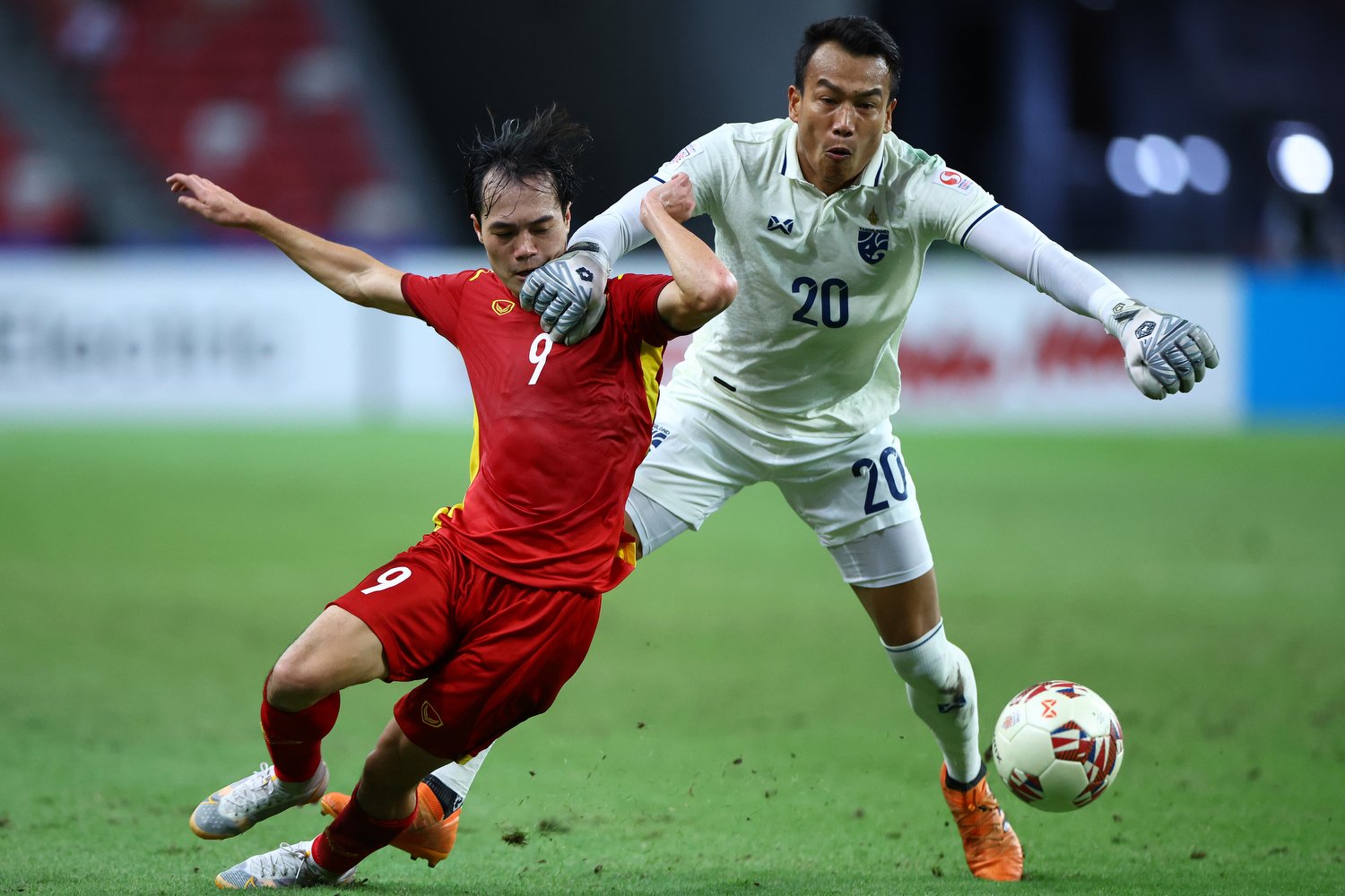  SINGAPORE, SINGAPORE - DECEMBER 23: Goalkeeper Chatchai Budprom #20 of Thailand pulls down Nguyen Van Toan #9 of Vietnam in the first half during the first leg of their AFF Suzuki Cup semifinal at the National Stadium on December 23, 2021 in Singapo