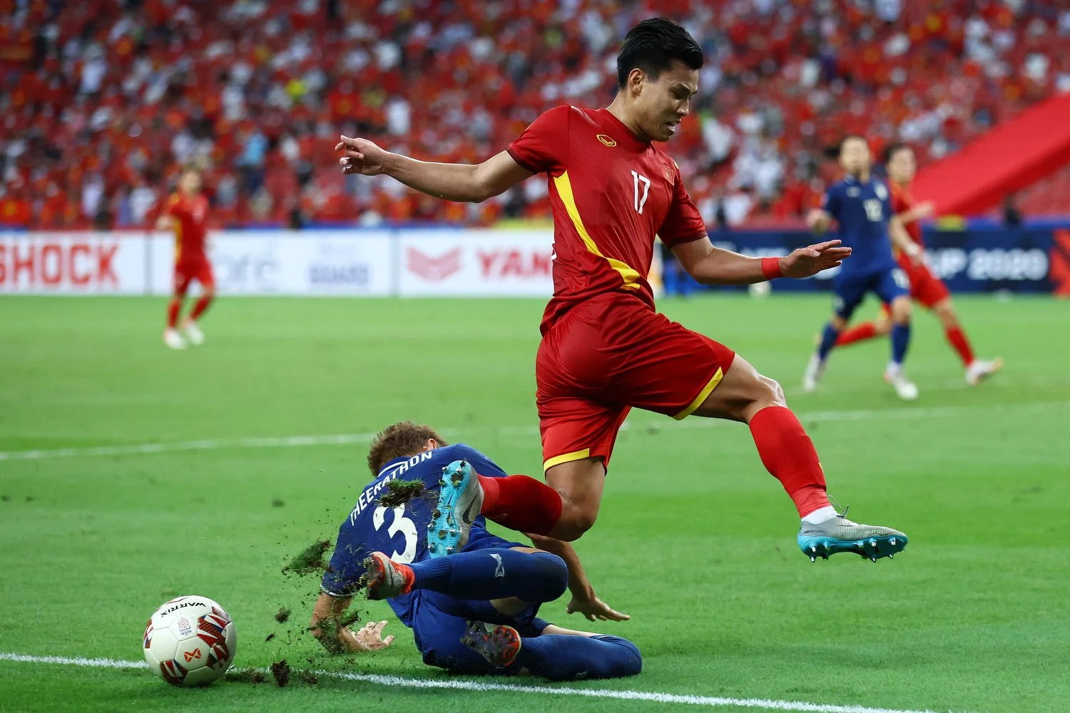  SINGAPORE, SINGAPORE - DECEMBER 23: Vu Van Thanh #17 of Vietnam is tackled by Theerathon Bunmathan #3 of Thailand in the first half during the first leg of their AFF Suzuki Cup semifinal at the National Stadium on December 23, 2021 in Singapore. (Ph
