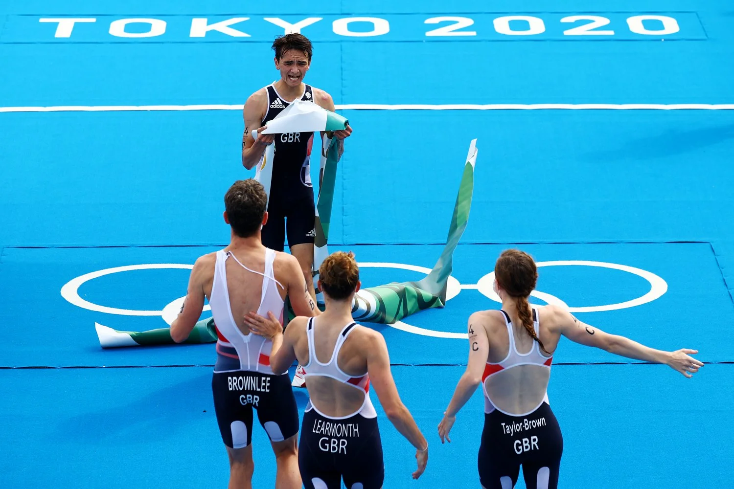  TOKYO, JAPAN - JULY 31: Alex Yee of Team Great Britain celebrates with teammates Jonathon Brownlee, Jessica Learmonth and Georgia Taylor-Brown after crossing the finish line to win gold in the Mixed Relay Triathlon on day eight of the Tokyo 2020 Oly