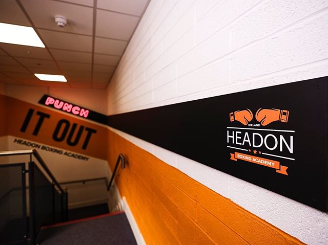 The blackboard entrance leading line starts with a Neon Punch and ends with the Headon Boxing Academy logo, also functioning as a notice board for class schedules. The main room is wrapped with an orange stripe that is capped with backlit HBA letters