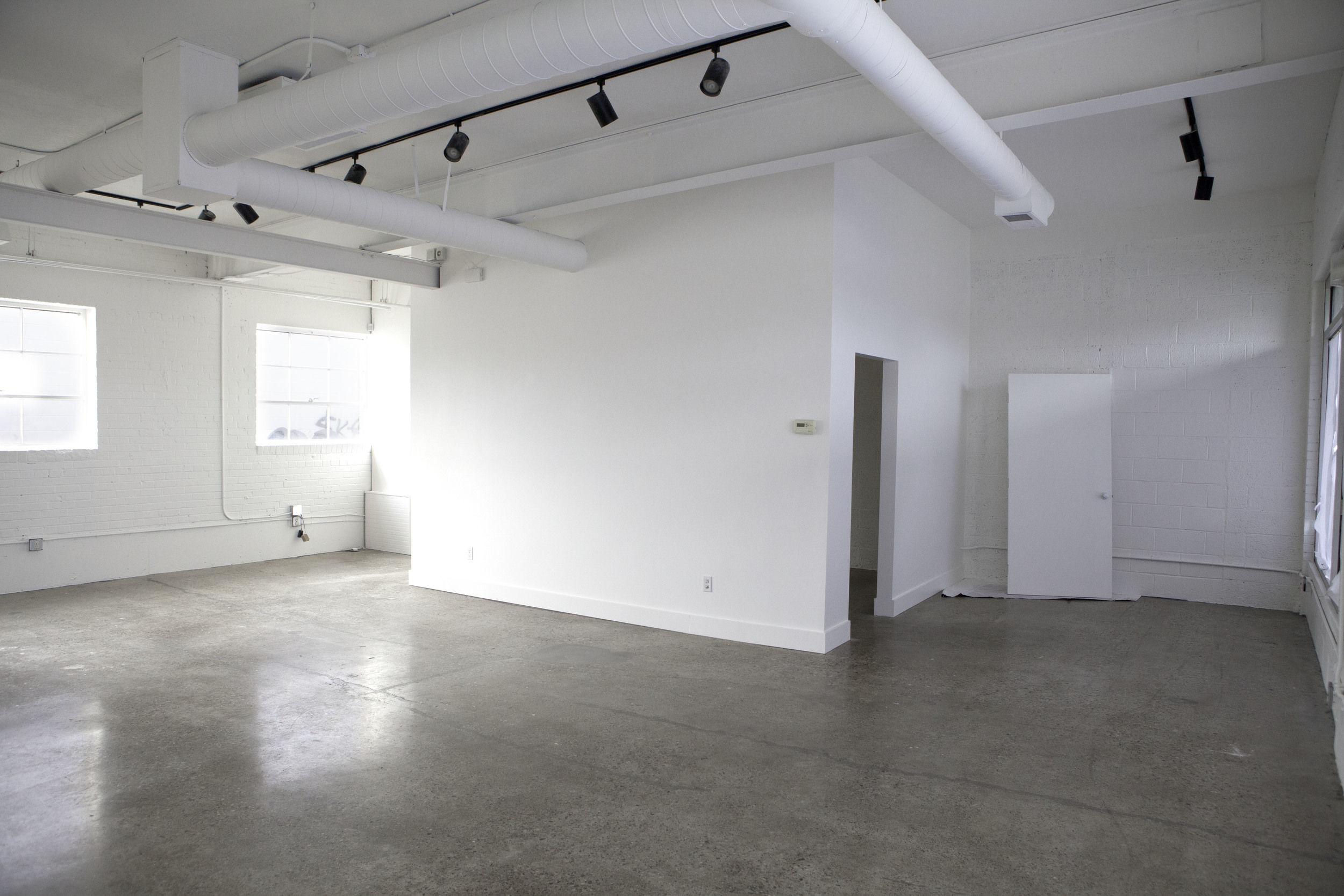 After the new wall/door way was built. White paint on walls and ceiling and floors ground down to the original concrete.