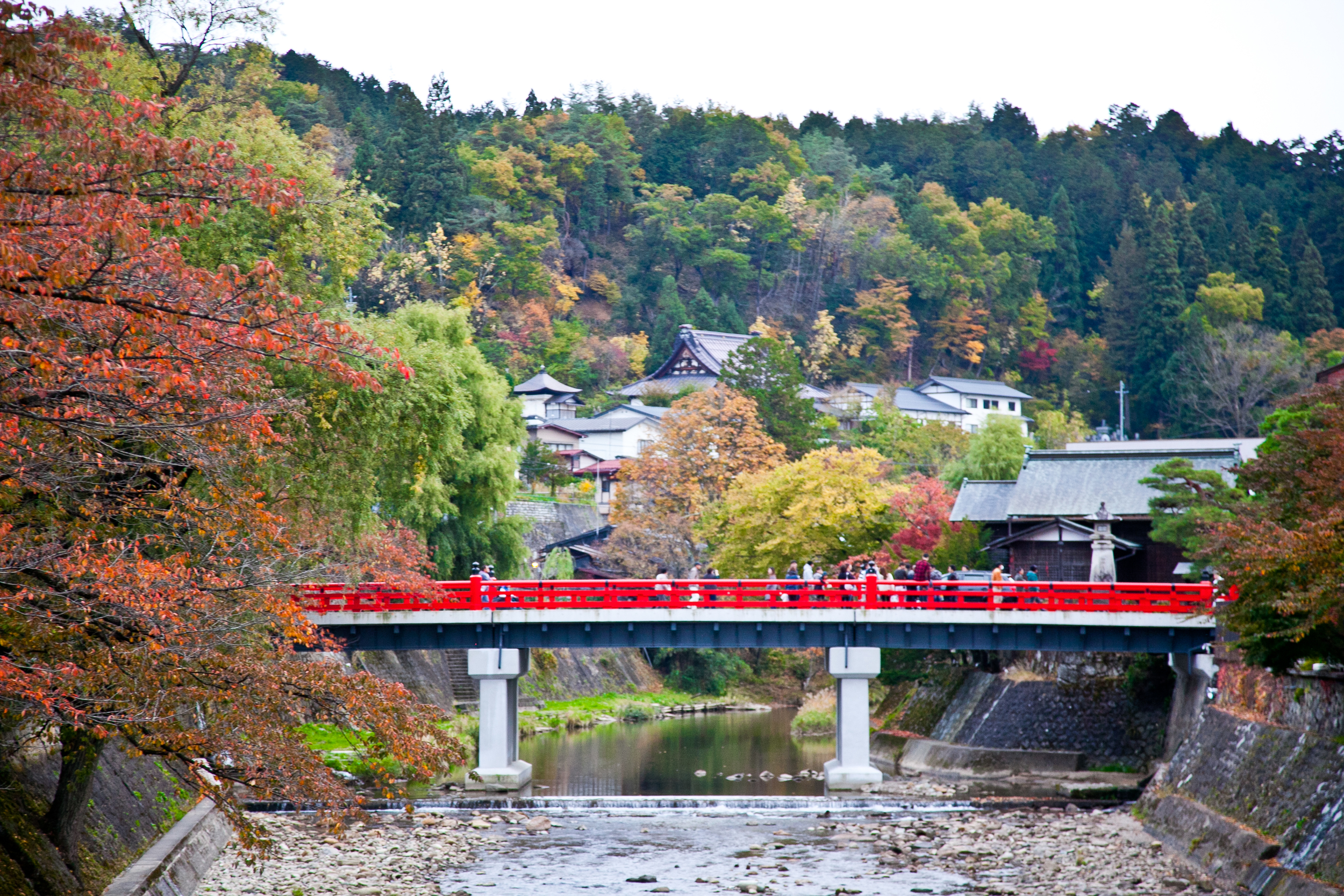 Takayama 's famous red bridge linking the modern side of town to the traditionally preserved districts