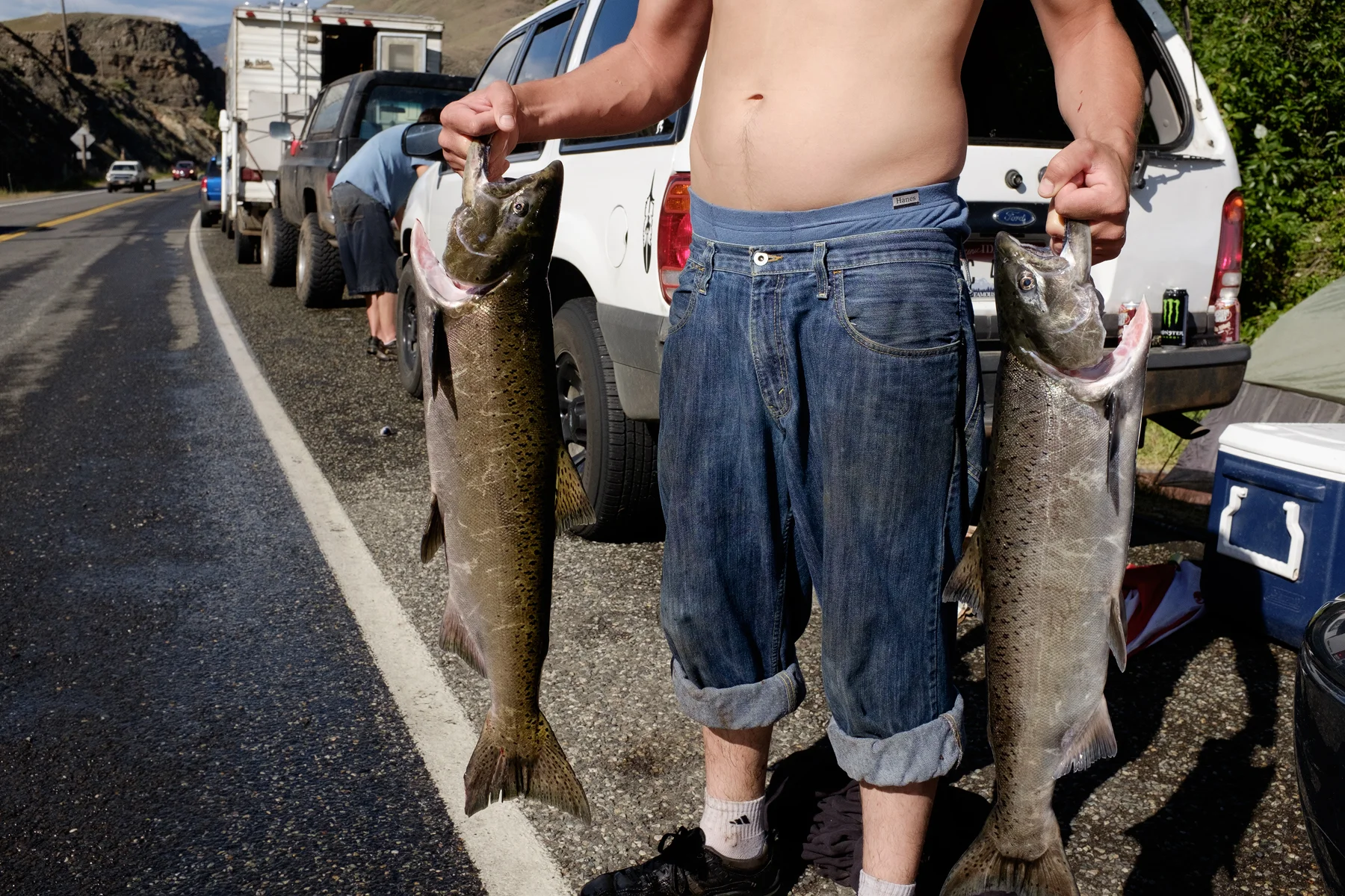 A young member of the Nez Perce tribe holds two Chinook Salmon. Riggins, Idaho, USA. Image ©Connor Stefanison