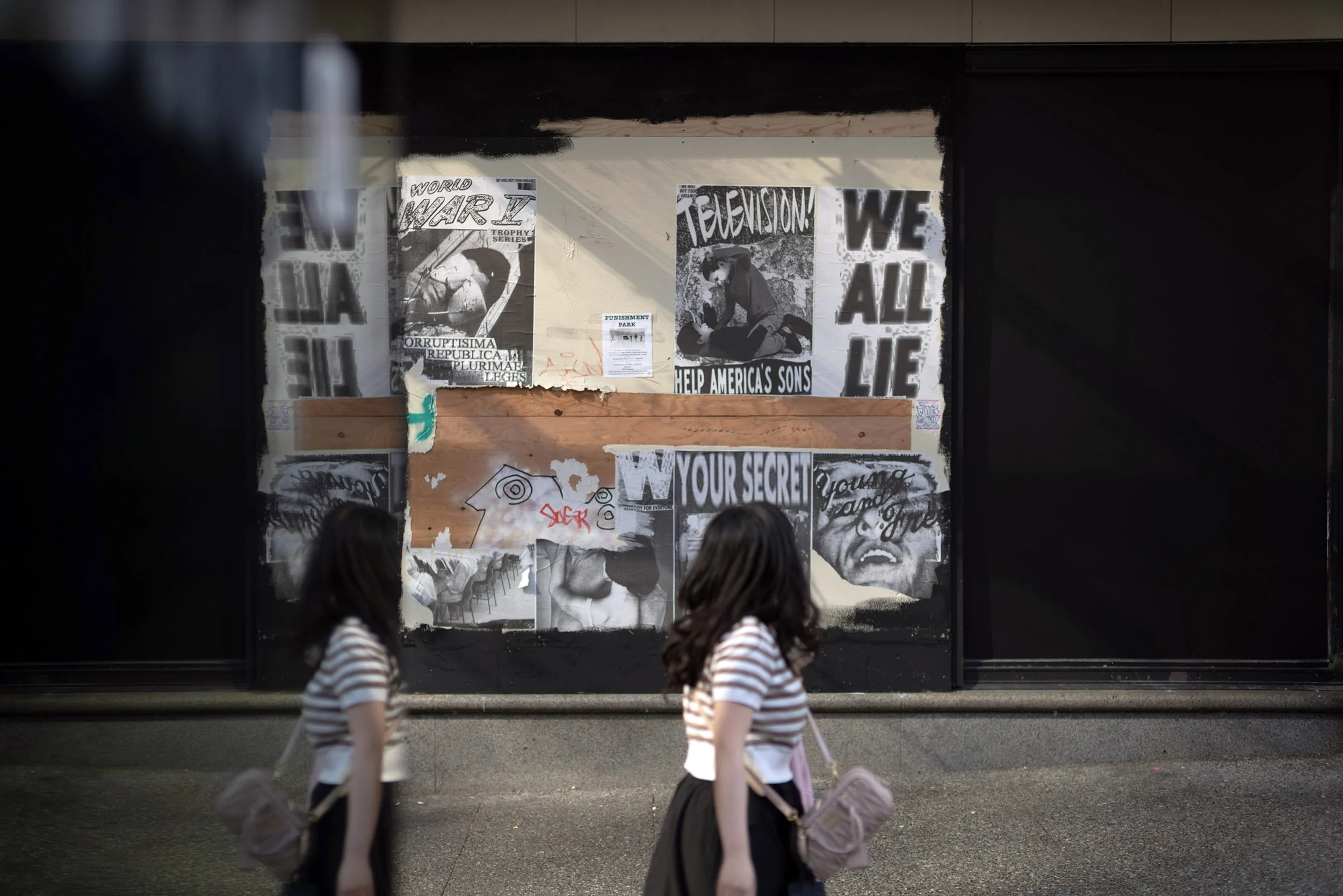 A young woman looks at posters along Granville Street in Vancouver. August 2026.