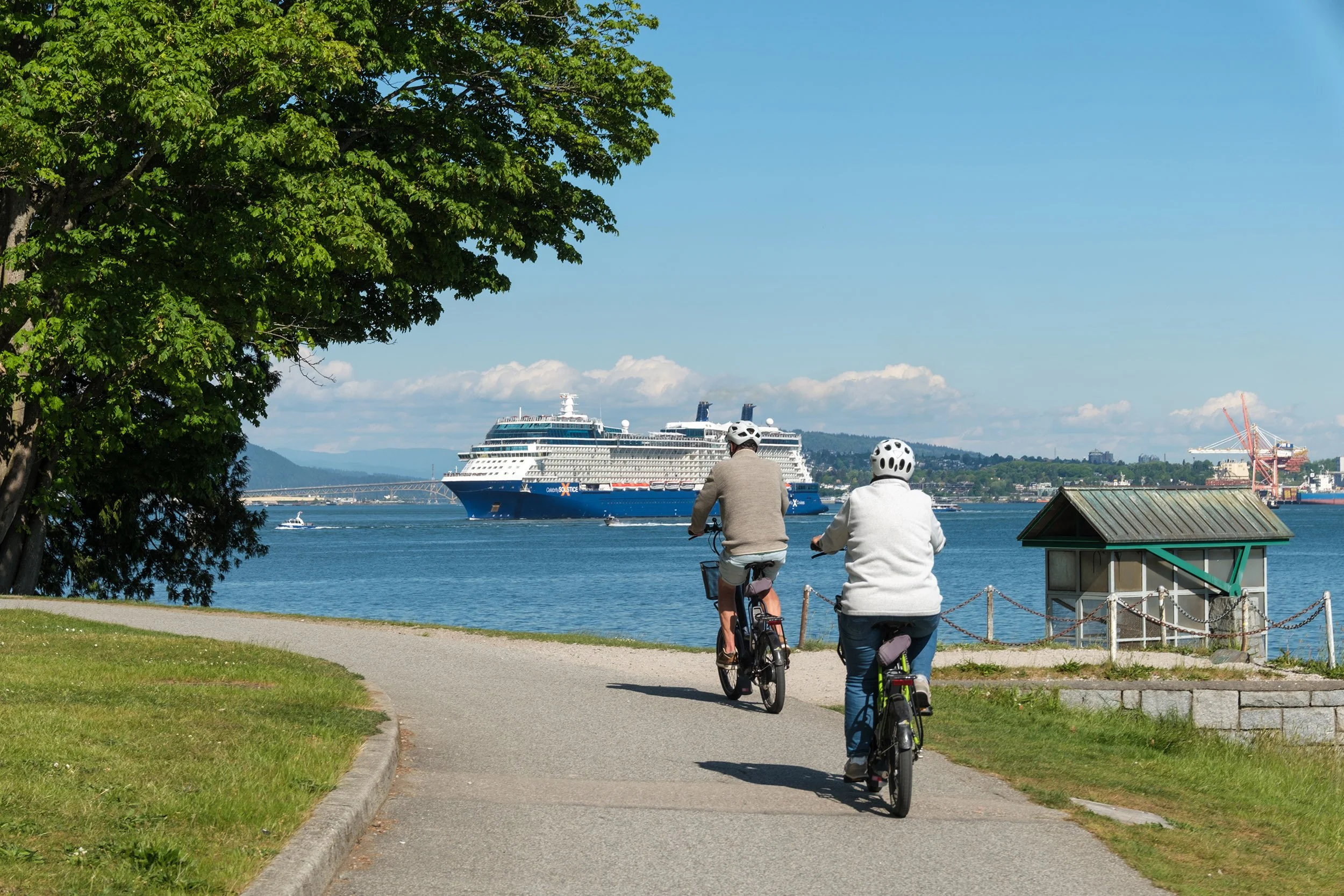 A middle ages couple bikes the Stanley Park Seawall as a cruise ship departs. Sample image from a Fujifilm X-T50 and XF 16-50mm f/2.8 R LM WR.