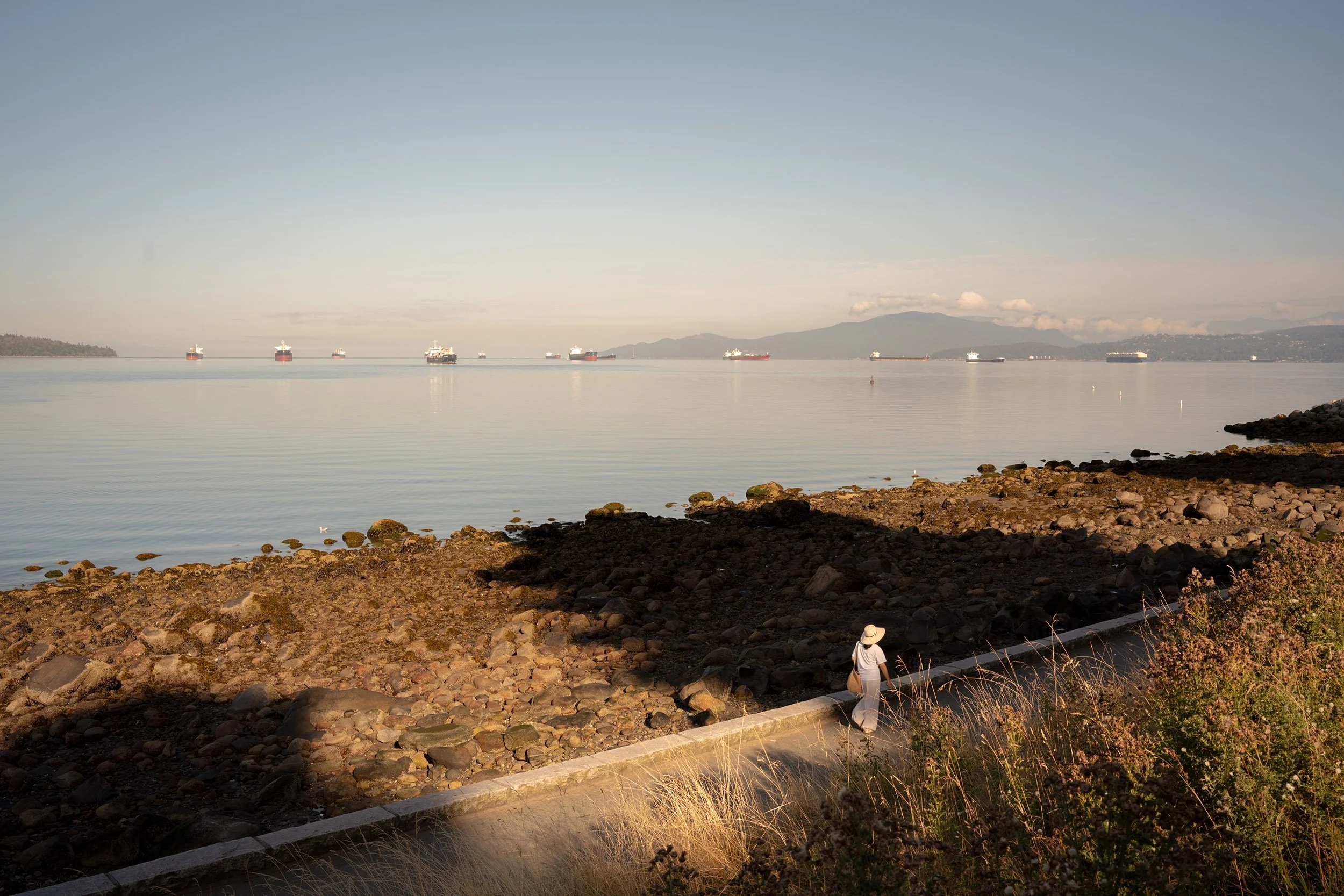 A woman walks the Stanley Park Seawall along English Bay. Sample image from a Sigma 35mm f/1.4 DG II Art and Sony A7V.