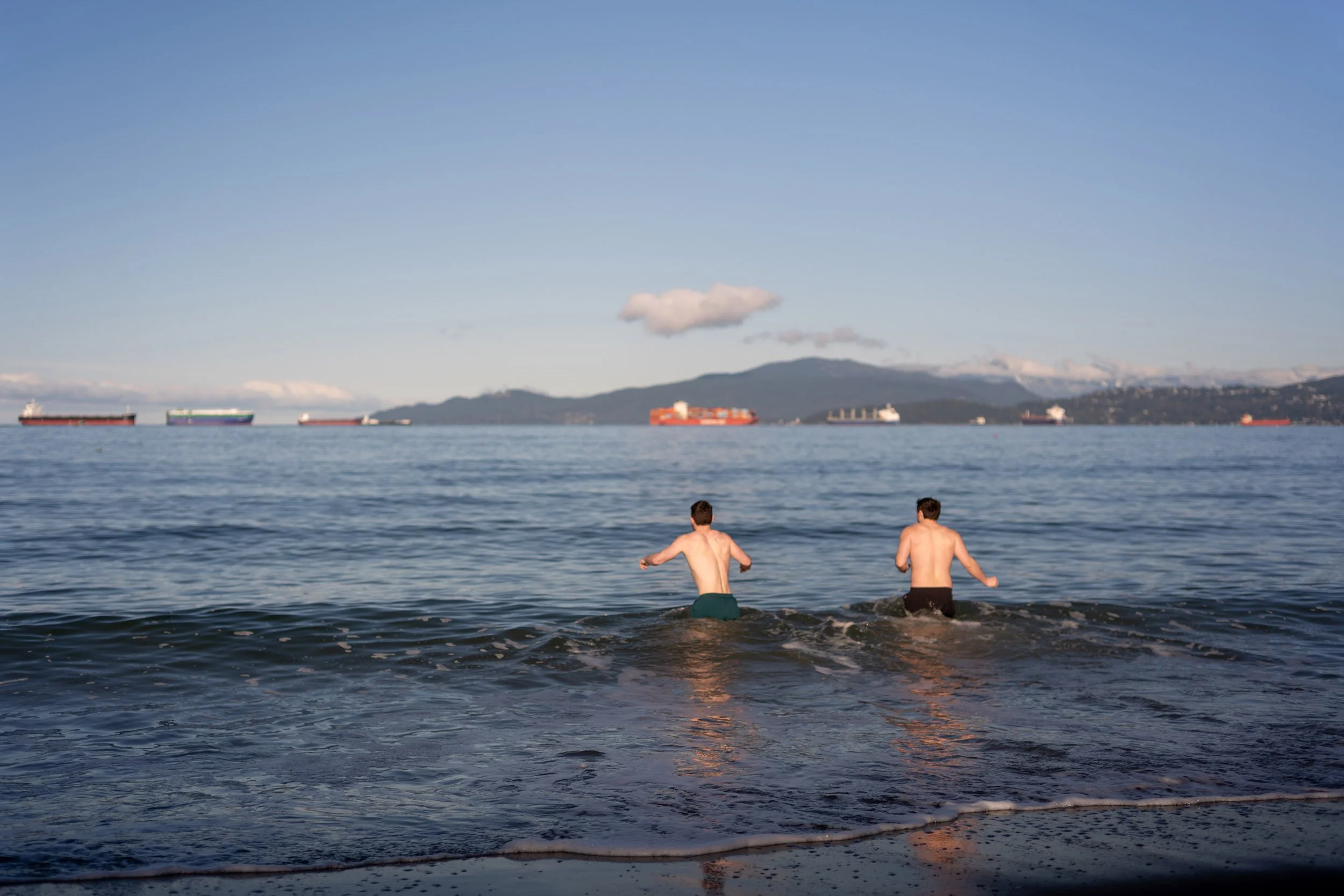 Two young men swimming at English Bay Beach, March 2026