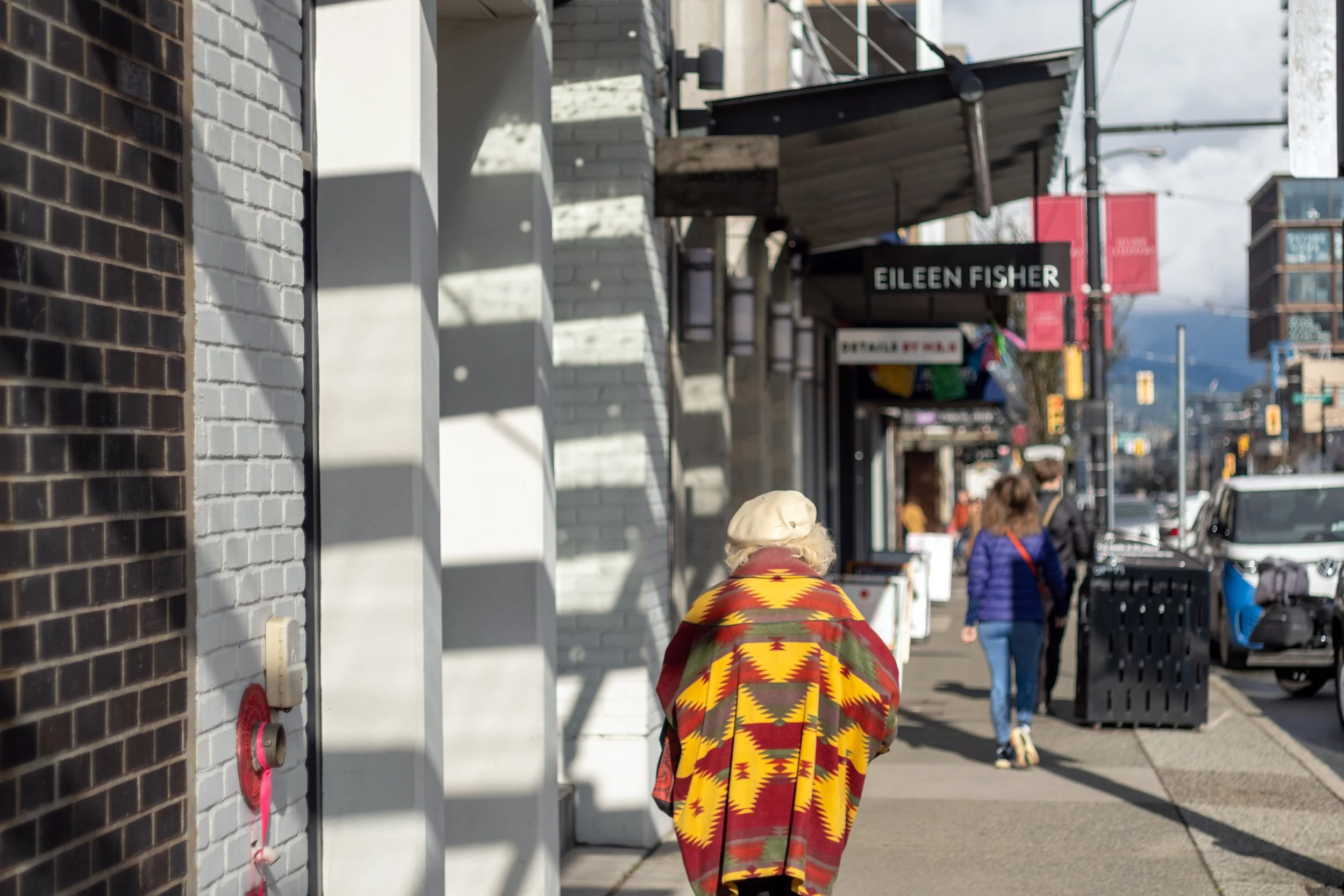 A woman walks down Granville Street on a sunny winter day in Vancouver.