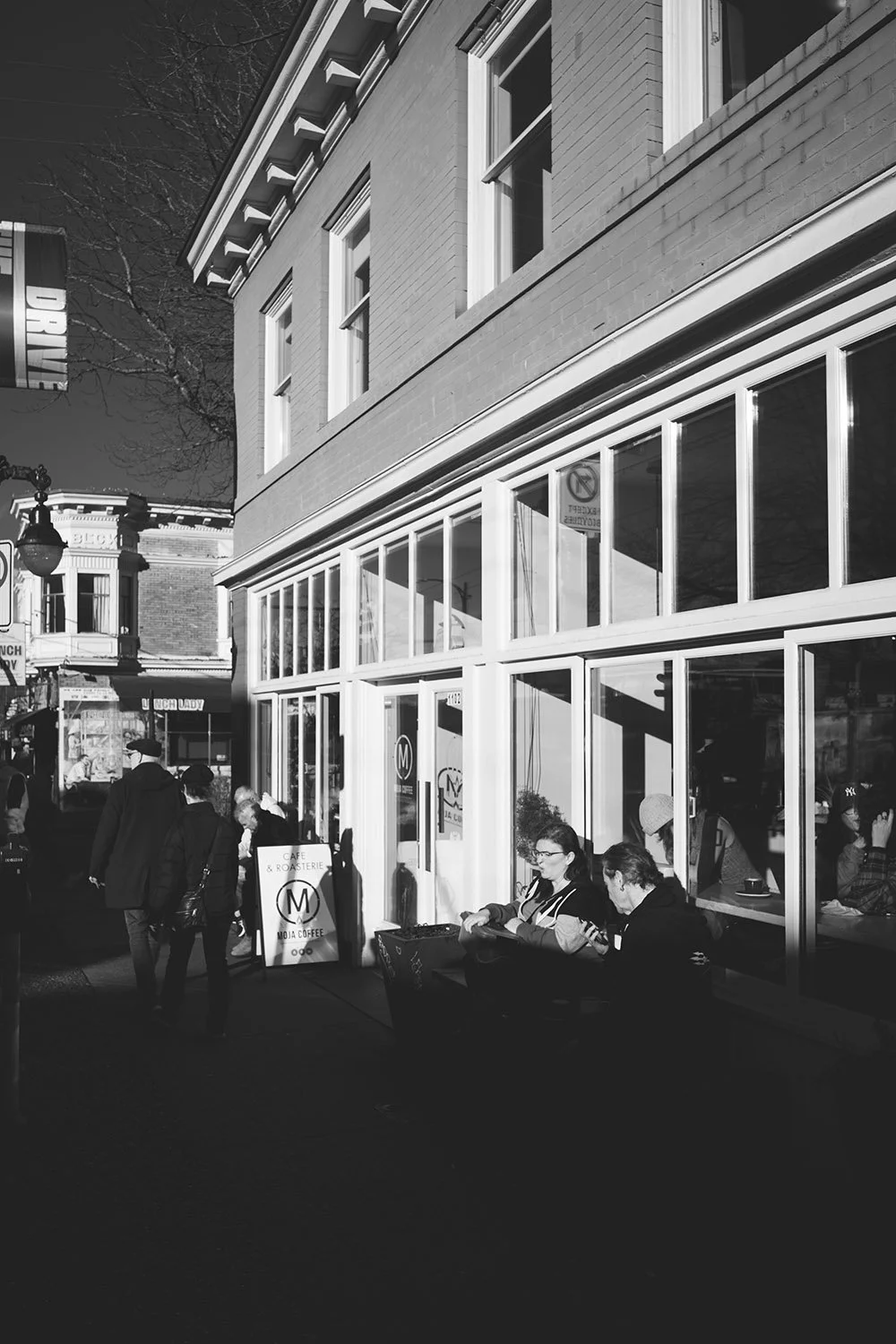 Patrons of Moja Coffee sit outside in the February sun along Commercial Drive in Vancouver. Sample image from a Voigtlander Nokton Vintage Line 28mm f/1.5 Aspherical and Leica SL2-S.