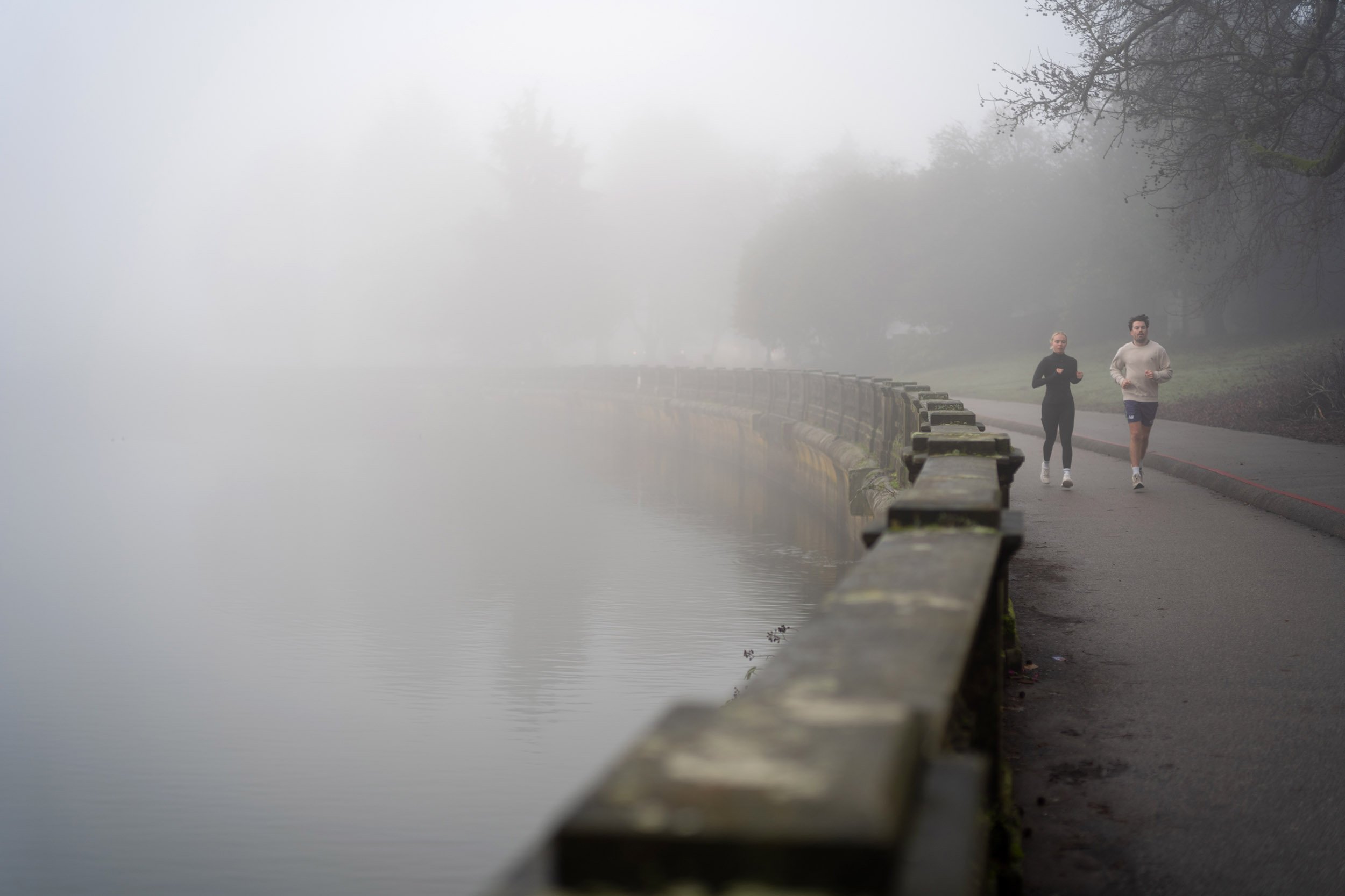 Runners along Stanley Park Seawall on a foggy morning.