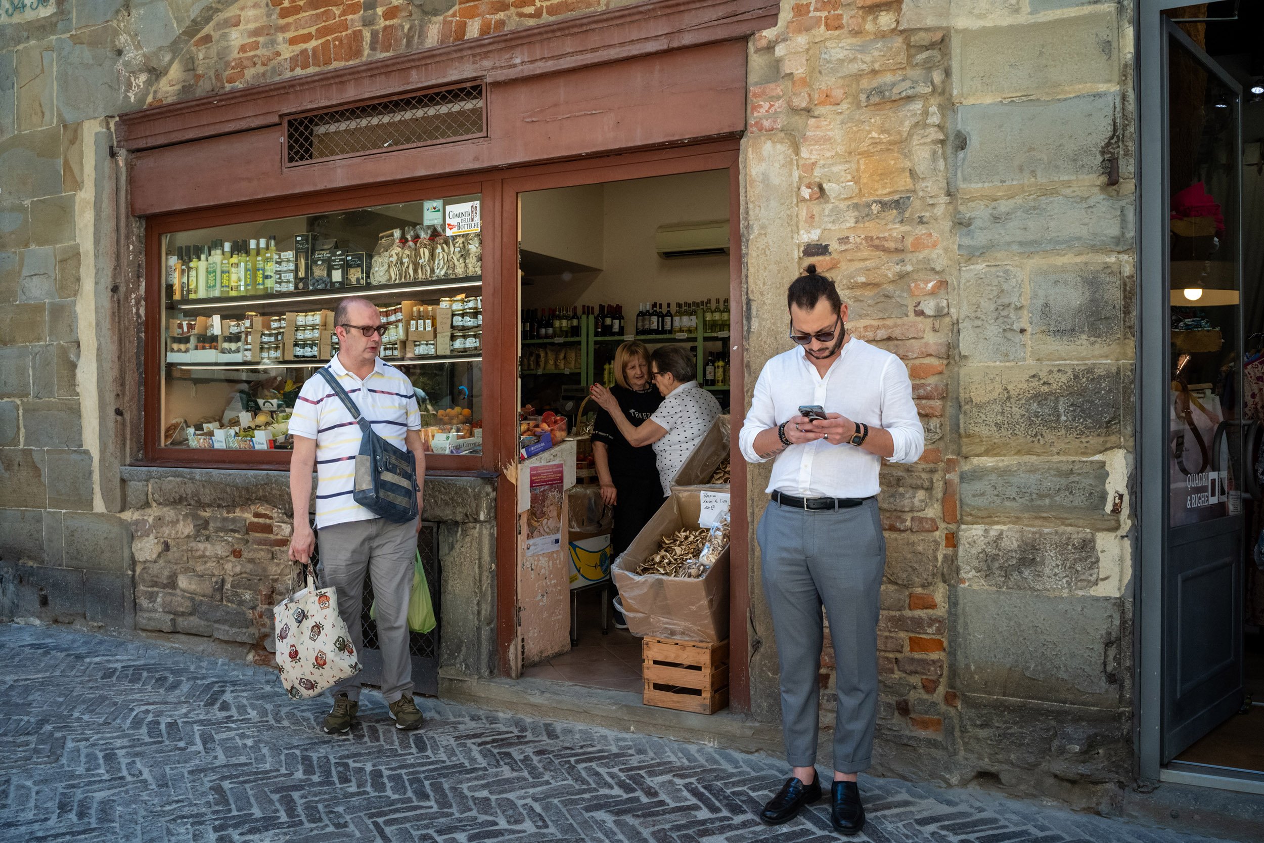 Two men are waiting outside a shop in Bergamo Italy. Sample image from a Voigtländer Nokton Vintage Line 28mm f/1.5 (M-Mount) and Leica SL2-S.
