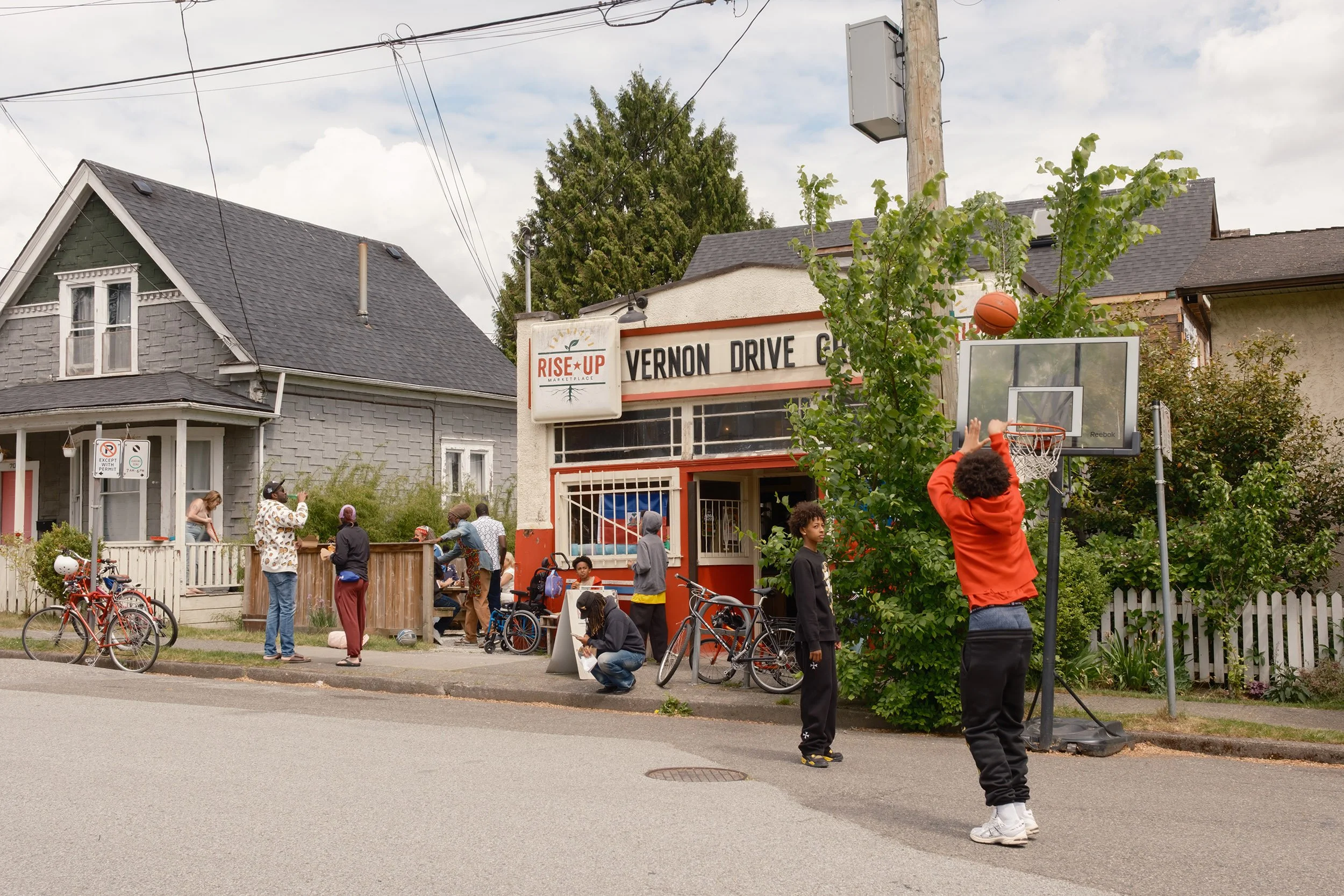 People hang out and kids play basket ball outside the Vernon Drive Grocery Store in Vancouver. May 18, 2026.