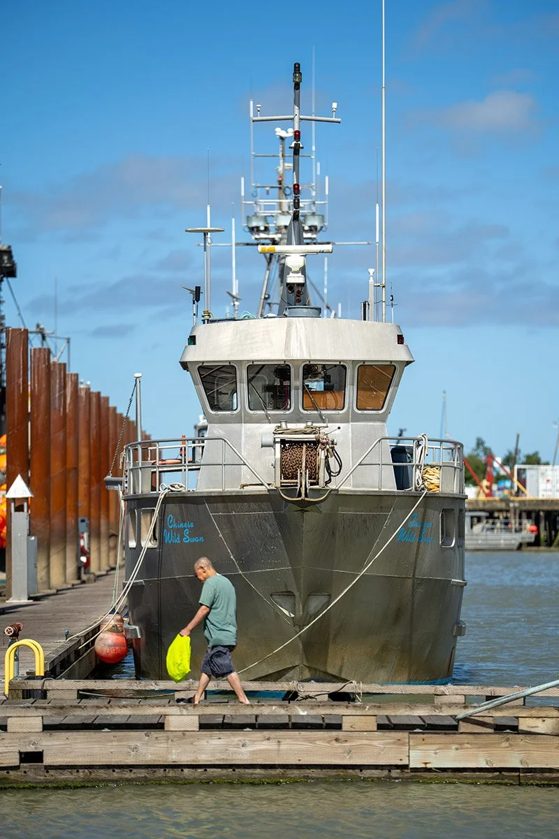 A man walks to a fishing boat in Steveston. Sample image from a Sony FE 50-150mm f/2 GM and Sony A7 V.