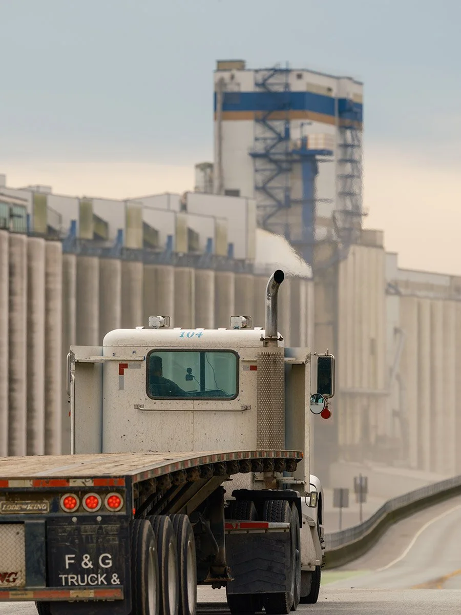 A transport truck drives along Low Level in road in North Vancouver by the Cargill Grain Terminal. Sample image from a Fujifilm GFX 100S II and Fujifilm GF 500mm f/5.6 R LM OIS WR.