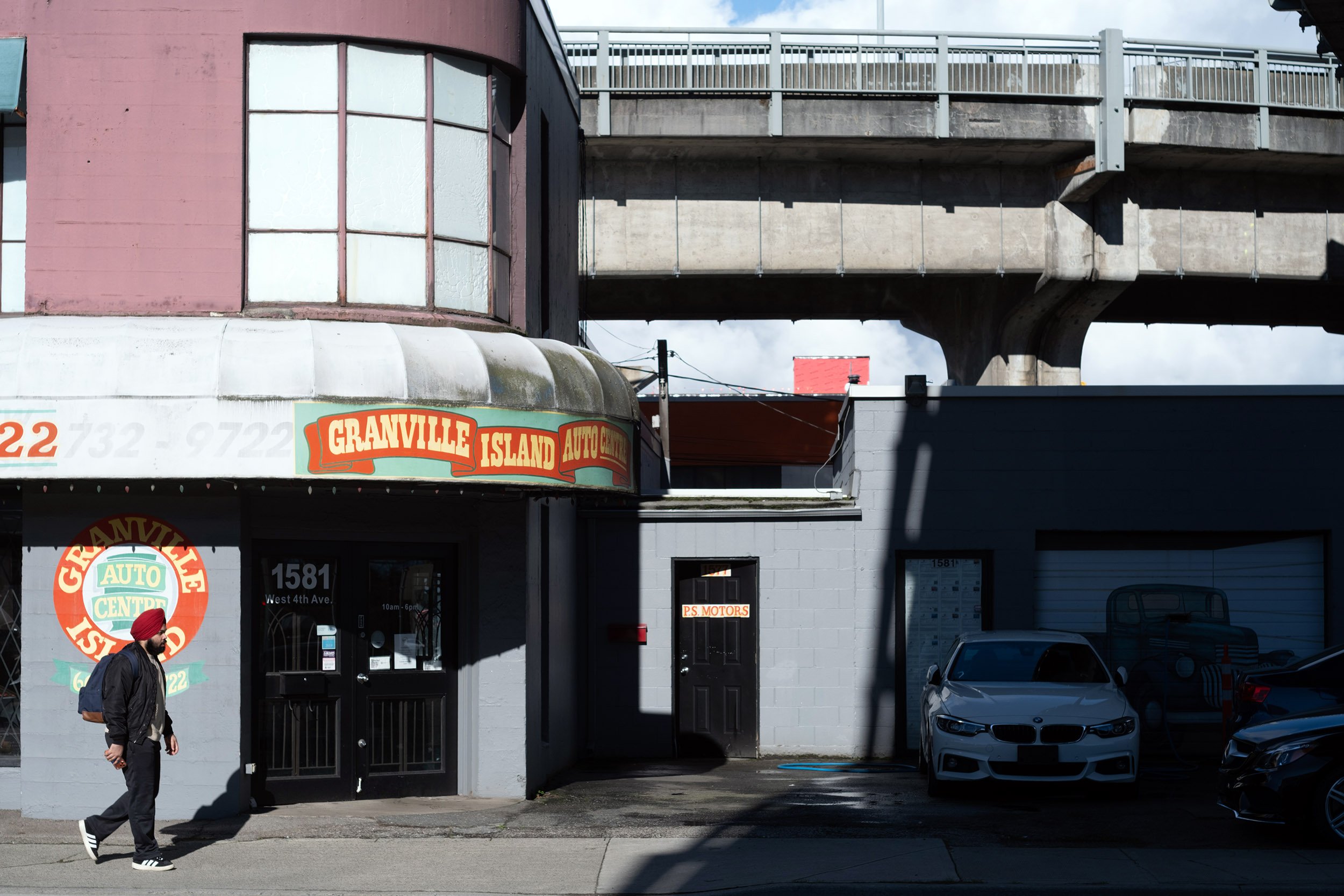 A pedestrian walks be a car dealer on West 4th Ave in Vancouver.