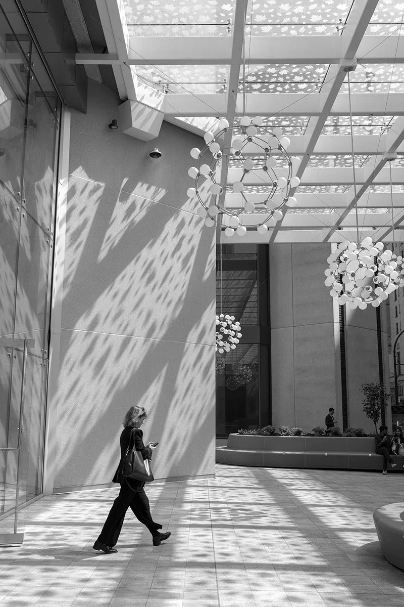 A woman exits an office building along West Georgia Street in Vancouver. Sample image from a Sigma 35mm f/1.4 DG II Art and Leica SL2-S.