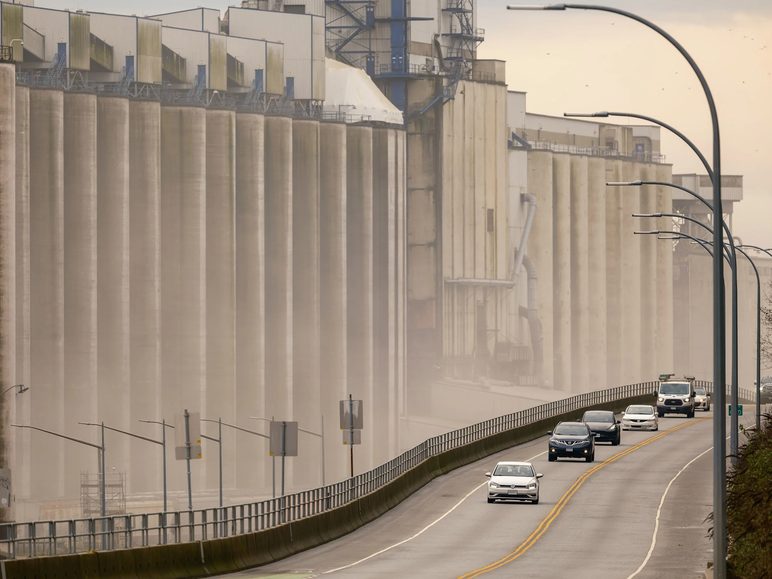 Car drives along the Cargill grain terminal on Low Level Road in North Vancouver. Sample image from a Fujifilm GF 500mm f/5.6 R LM OIS WR and Fujifilm GFX 100S II.