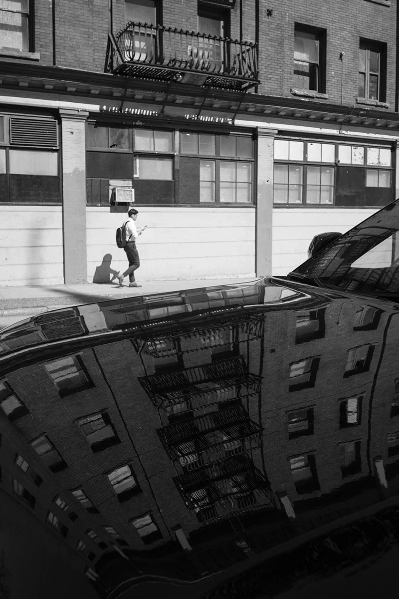A man walks down the street and car reflection. Sample image from a Voigtländer Nokton Vintage Line 28mm f/1.5 (M-Mount) and Leica SL2-S.