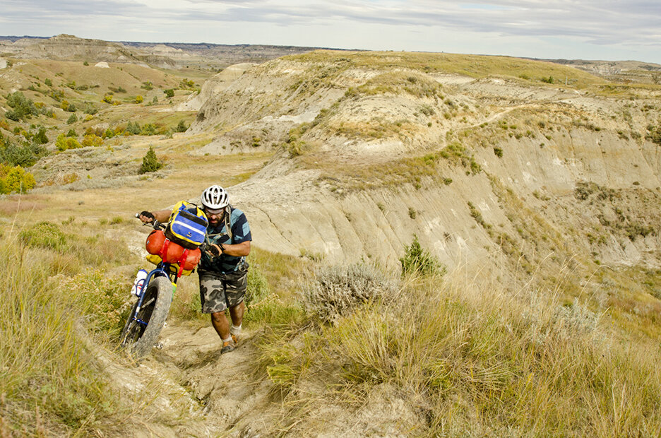 Dustin Allebach of Minneapolis, Minn., pushes his bike up a steep hill while on a bike packing trip on the Maah Daah Hey trail in North Dakota, Sunday, Sept. 29, 2013.