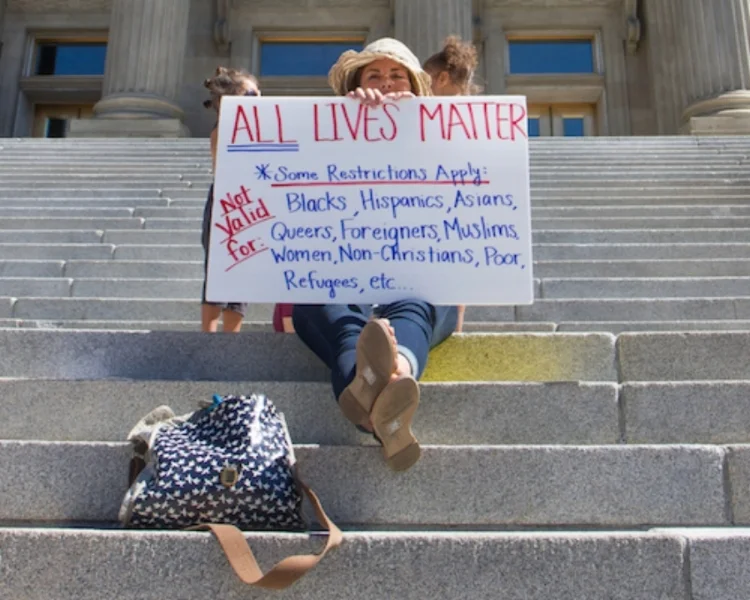 PHOTO COURTESY OF ISTOCK BY GETTY IMAGES: Boise, USA- July 16, 2016: Woman holds an All lives matter showing the irony of the statement (This post was originally run on The Huffington Post on October 16, 2016.) This country is in deep turmoil when it comes to the topic of race. While the incidences of continued and increased police brutality highlight this fact, and seem to continue to do so, the Presidential debates have been another arena for this topic. While Trump touts stop-and-frisk as the best way to stop crime, he completely neglects the fact that this policy unfairly targets minorities . Maybe he is uneducated in this arena. However, more likely he is just completely ignorant, pushing aside the facts, including a Guardian finding that “32% of black people killed by police in 2015 were unarmed, as were 25% of Hispanic and Latino people, compared with 15% of white people”. Trump’s continued nonsensical comments, such as those equating inner cities with African-Americans and thus violence, are not only untrue, as most African-Americans actually live in suburbs, but scary. In essence, it speaks to the assumptions and presumptions that much of this country holds as they pertain to not only African-Americans, but minorities overall. Over and over again, the Presidential Candidates and their running mates have referenced the term “implicit bias” , which encompasses associations that are not fully conscious, as being a contributing factor to why race relations is in its current state. However, as John Powell so eloquently points out in the Berkeley Blog , “Bias is part of being human. Racialized consequences of harmful implicit biases are not. And the content and strength of particular biases are socially constructed.” In other words, our environment, which includes everything from the upbringing in our homes to our communities, shapes implicit bias and the actions that follow. So, while I do credit the Presidential debates for bringing implicit bias and racism to the forefront, awareness and education around this topic will by no means solve today’s racial divide. We will never be bias free, nor should we be, for without biases, we could spend inordinate amounts of hours on everyday menial tasks. HOWEVER, as a country,we can begin to eradicate the conditions that impact implicit and racial biasby, for example, implementing measures and solutions to revamp the outdated infrastructure that fails to mediate the increased violence, police brutality, and isolation of and bias against our inner cities and communities of color. As a former public school teacher in various socioeconomic settings, I have witnessed the gaping inequities between inner city and suburban schools. As a 22-year old teacher in inner city Boston, I had a 15-year old student with a newborn baby at home and another female student who had been molested. When I approached the Principal about forming a support group for girls facing issues such as this, he refused. In a more responsive school setting, this sort of group would be implemented. At the same time, I worked alongside colleagues who referred to students as “hopeless” and “stupid,” giving them rote tasks such as copying to “calm them down”. Needless to say, I was shocked and appalled. Compared to my public school experience, which was filled with demanding and caring teachers, extra curricular options and an outstanding college preparatory curriculum, these students really had no access to opportunity from an early age. It just so happened that, in 1996, most of these students were also minorities. I share all of the above as one key to fixing America’s pitiful and misunderstood backdrop around race is education. I know this not only from my experience as a public school teacher, but also from my work as a Diversity and Inclusion professional. Time and time again I have sat around the table with very educated tech professionals at some of Fortune’s 100 Best Companies to Work For , and heard the same comment when it comes to hiring diverse talent: “We don’t want to lower the bar for quality.” Every time I hear this statement, I want to scream, but instead calmly remind people that race, or any other physical trait, is by no means equated with quality. But, somehow, this myth exists across not only Silicon Valley, but our entire country. And to be very clear, there is plenty of qualified diverse talent. The Hispanic Heritage Foundation , for example, has a network of thousands of qualified Latino talent, inclusive of engineering students and professionals. I also remind clients that the playing field is not level and as such, companies need to not only expand their sources to include schools outside the typical Ivy leagues, but also commit dedicated resources to find this smaller percentage of talent. While Trump blames the African-American communities for the racism they face, Clinton on the other hand realizes that this is a systemic issue that requires multiple measures, including community policing and federal legislation to end racial profiling . These types of measures, among many others, are what is needed to mitigate implicit bias. So, while it is reassuring that implicit bias has been acknowledged in the Presidential arena, it is also just the beginning of a very long battle to fight and solve a systemic issue that has unfairly impacted all minorities for too many decades. It also highlights the fact that this nation is extremely uneducated and biased when it comes to preconceptions about race; for instance Trump’s appealing to a mostly African-American crowd in Virginia with statements such as, “What do you have to lose by trying something new…You’re living in your poverty, your schools are no good, you have no jobs, 58 percent of your youth is unemployed — what the hell do you have to lose?” The truth of the matter is that the majority of African-Americans do not live in poverty. Again, bias, in the form of Trump, has reared its not so beautiful combed-over head too many times. With all of this said, Trump is right about one thing: this country is a mess and is in dire need of change. What he fails to acknowledge though is that the change that is needed is positive, not negative, and in the form of solutions, not rhetoric and blame. And now is the time to start doing something about it. So, Mr. Trump, let’s indeed “Make America Great Again” and let’s begin by providing everyone access to opportunity. Now that’s something I will vote for on Election Day.