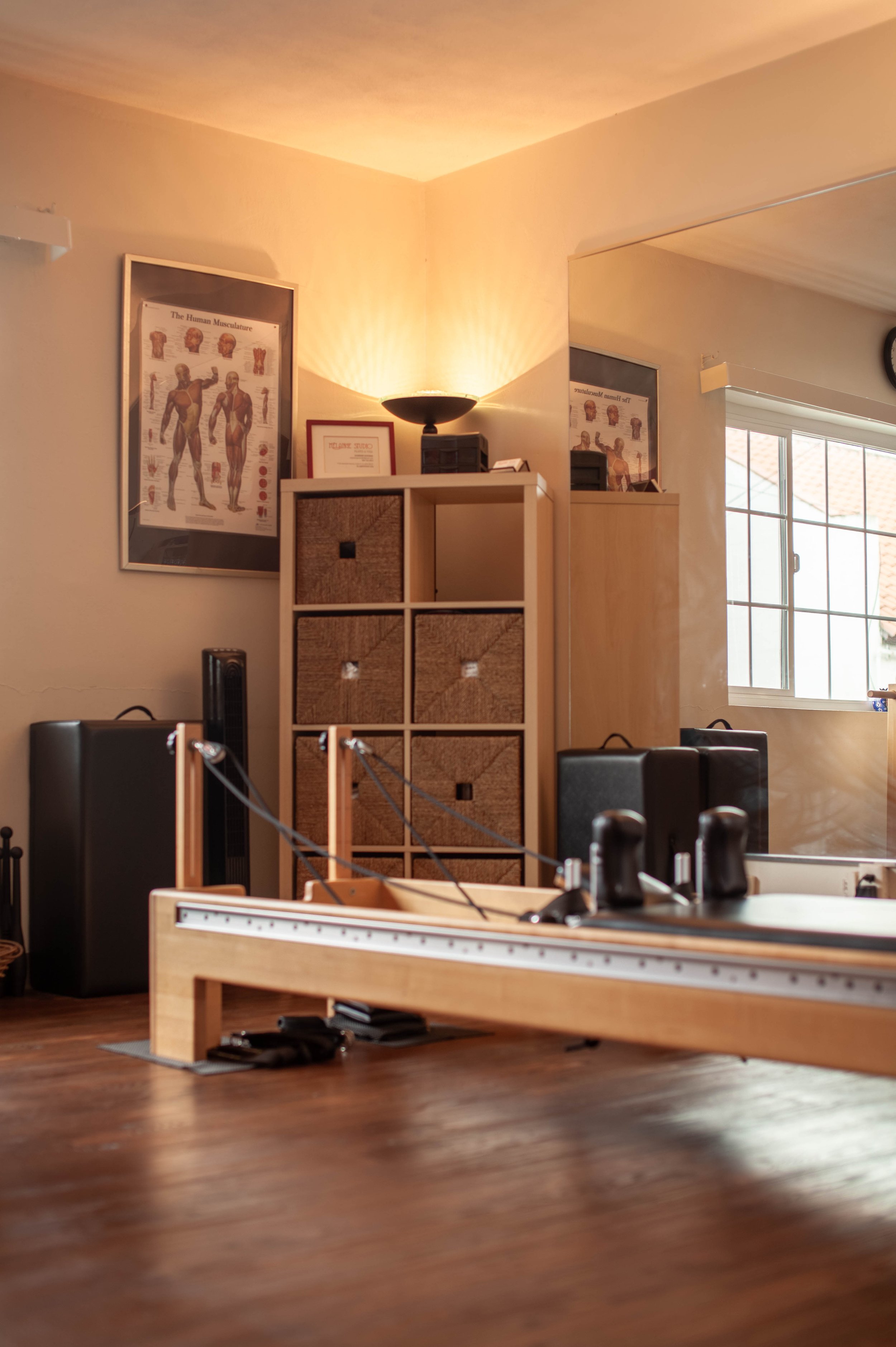 Image of studio corner with pilates reformer, warm lighting