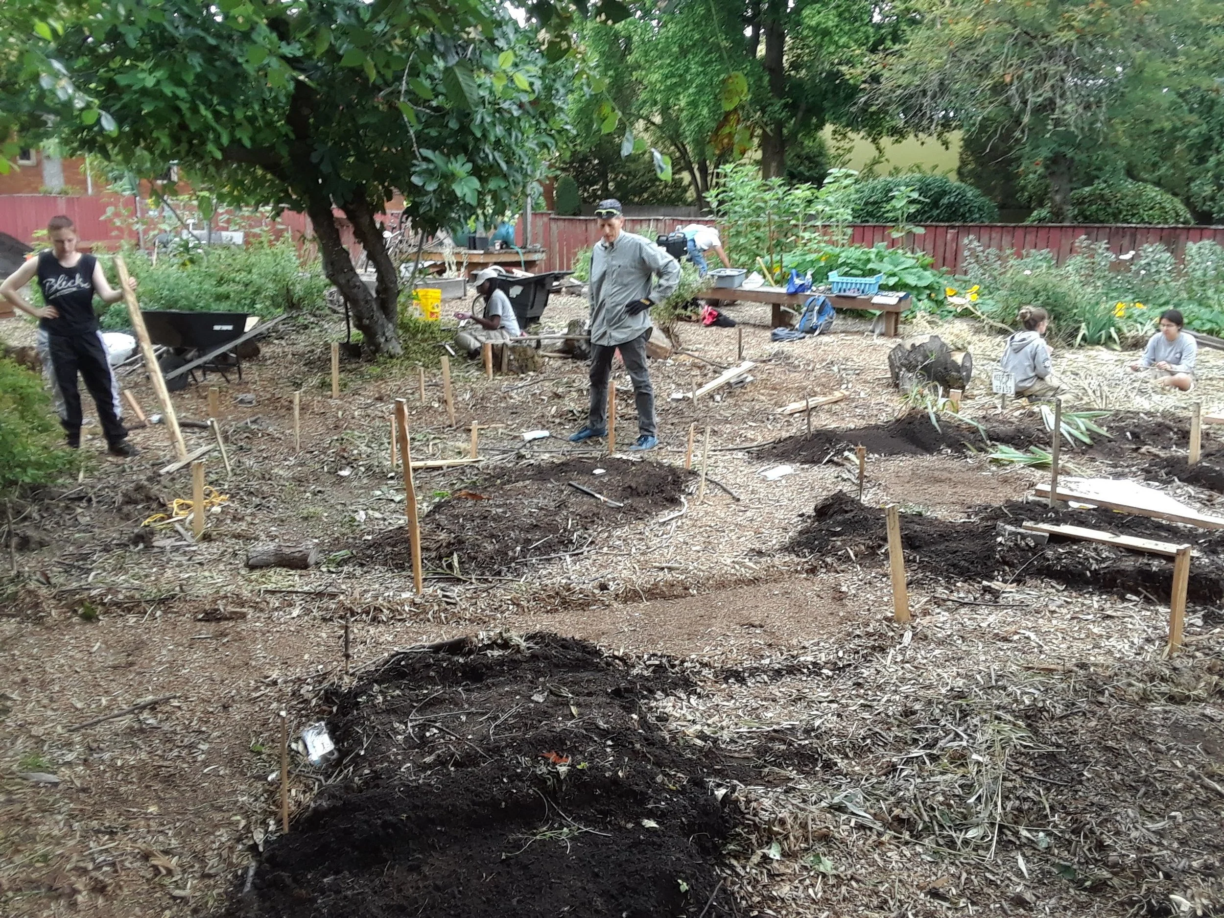 On far left, Communitecture/City Repair intern, Tess O’Day, collaborates with volunteers to install her design for the herb labyrinth.