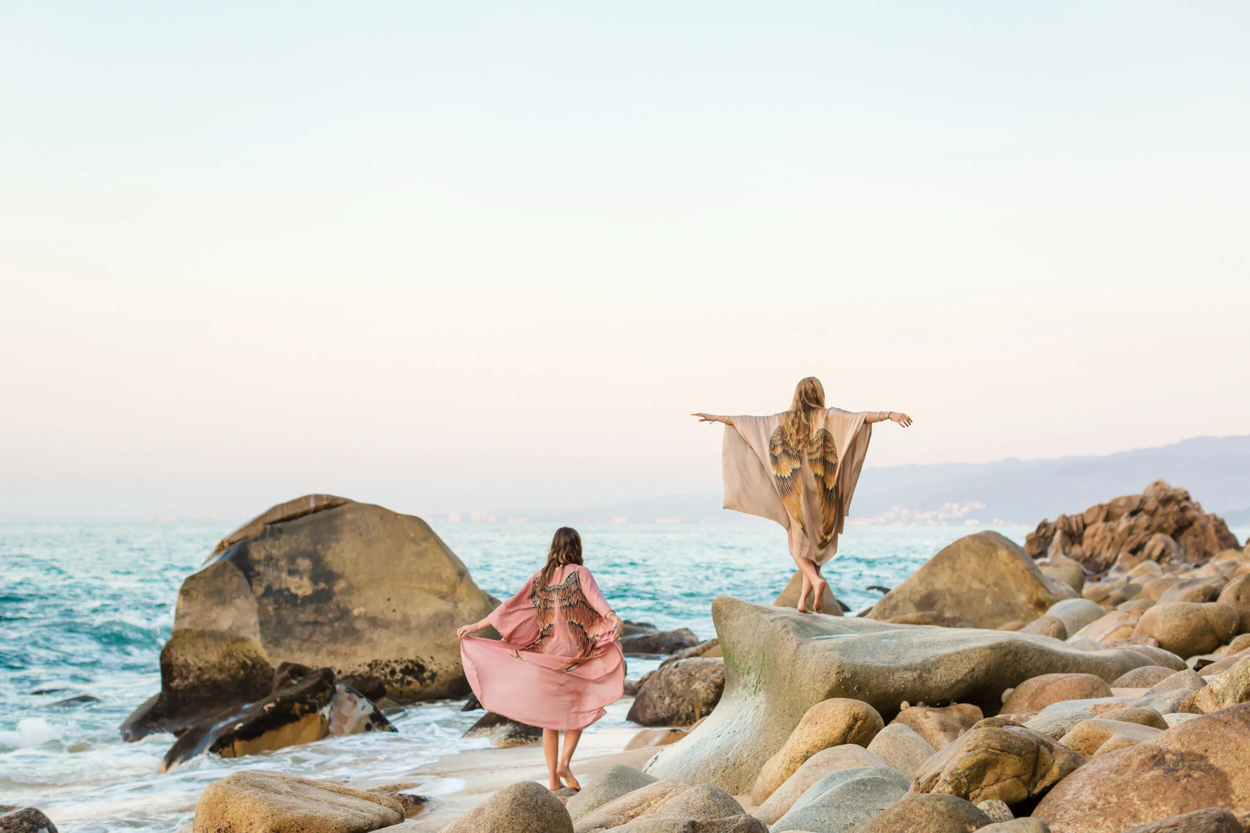  Two women frolicking on the beach in sustainable brand Warriors of the Divine angel wings at sunset photography in Puerto Vallarta Mexico 