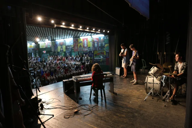 A Sub-Junior boy plays "Penny Lane" by the Beatles on the piano accompanied by boys' music staff.