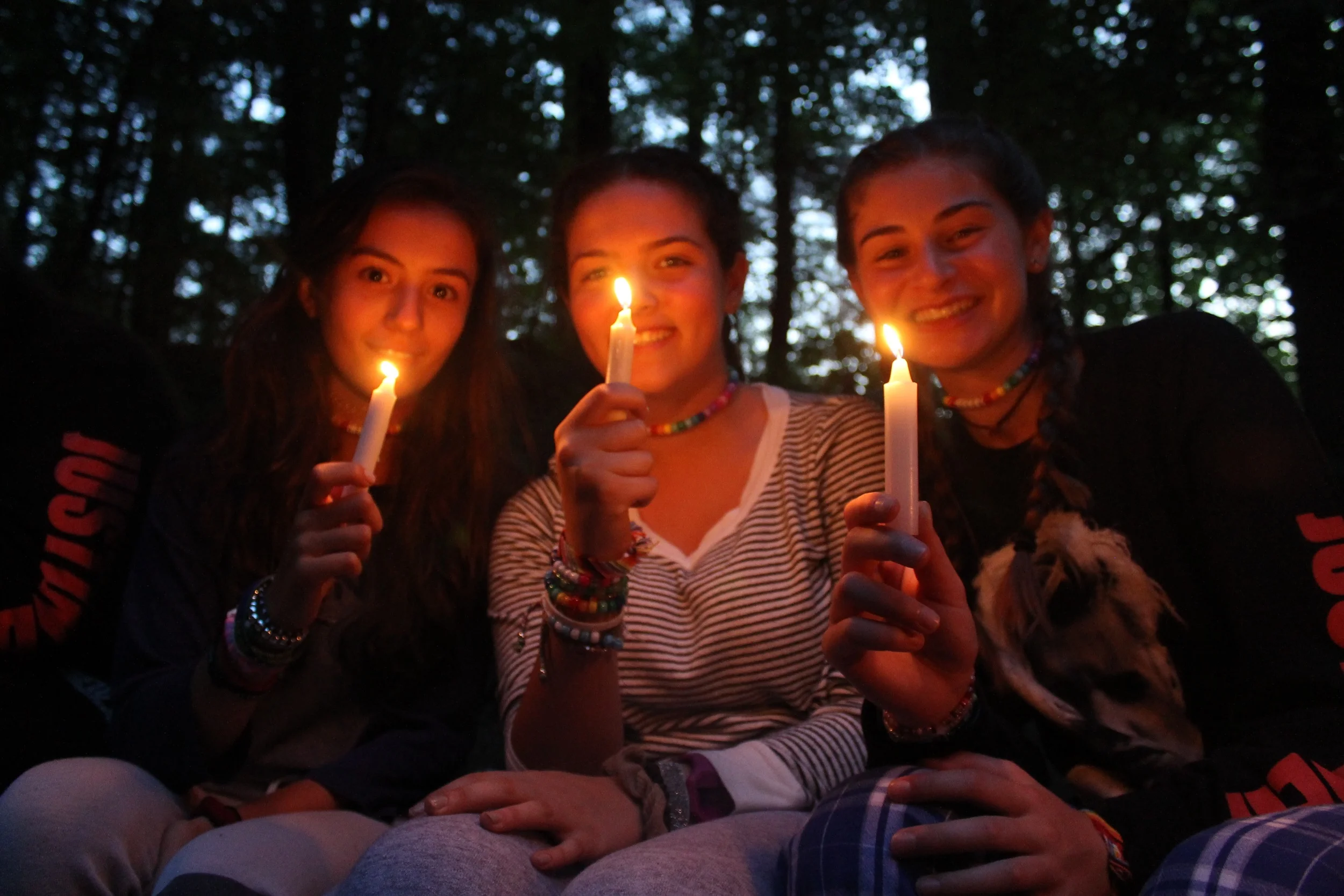 Senior girls light their candles at the end of the campfire to make a wish. 