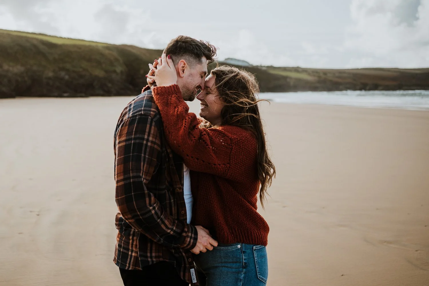 A couple on the beach, touching foreheads and smiling. Natural Engagement Photos