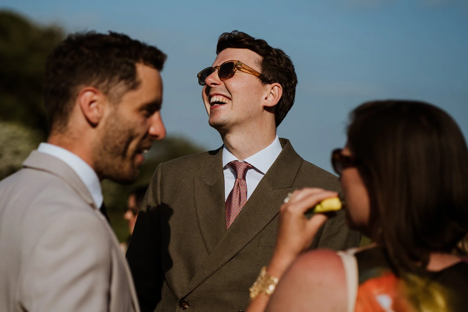 Wedding guests engaged in conversation and smiling, dressed in formal attire.