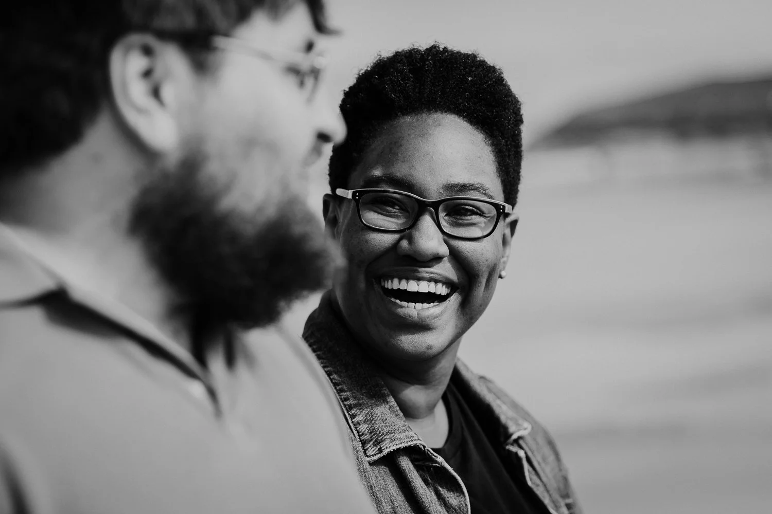 A black-and-white photo of a couple smiling and engaging in conversation outdoors. Black and White Photo. Couple Portrait Session