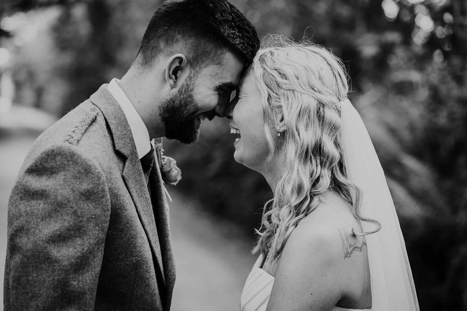 Black and white photo of a smiling bride and groom with foreheads touching. Natural Wedding Couple Portrait