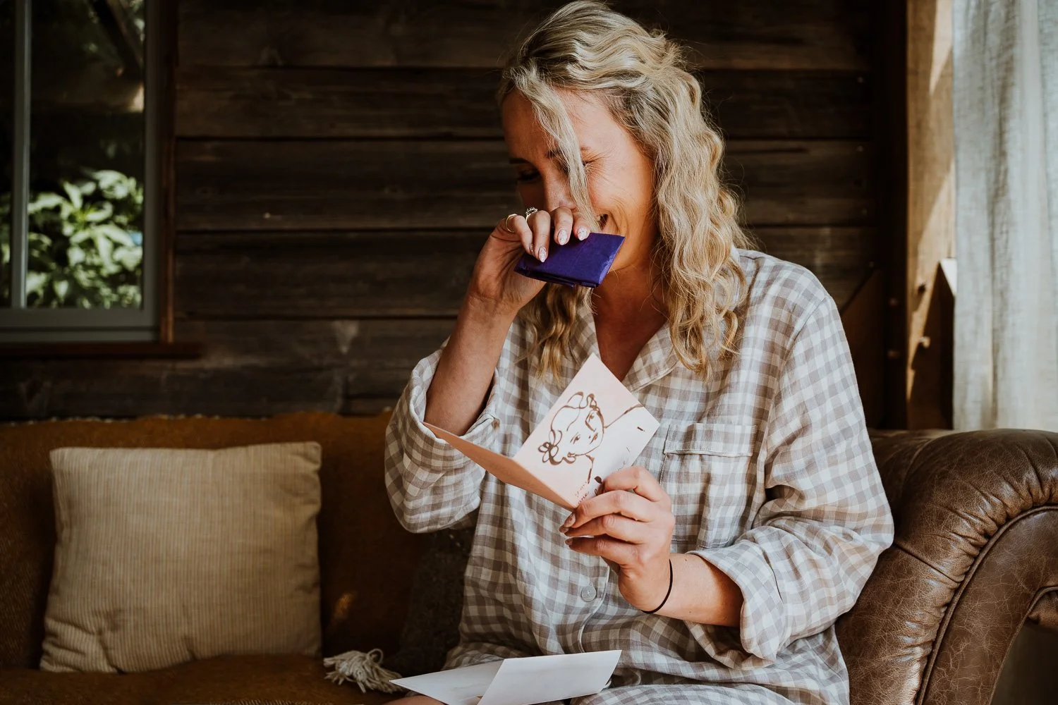 A bride captured crying tears of joy reading a card from her fiancé the groom. real emotions captured during wedding preparation photos 
