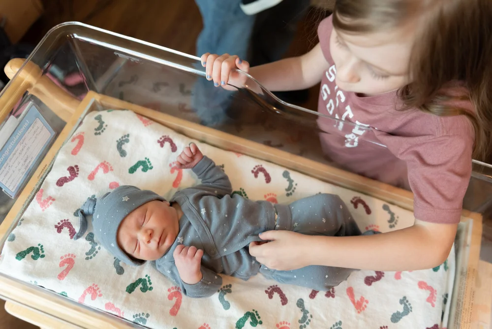 Hospital newborn storytelling image with older sibling meeting baby