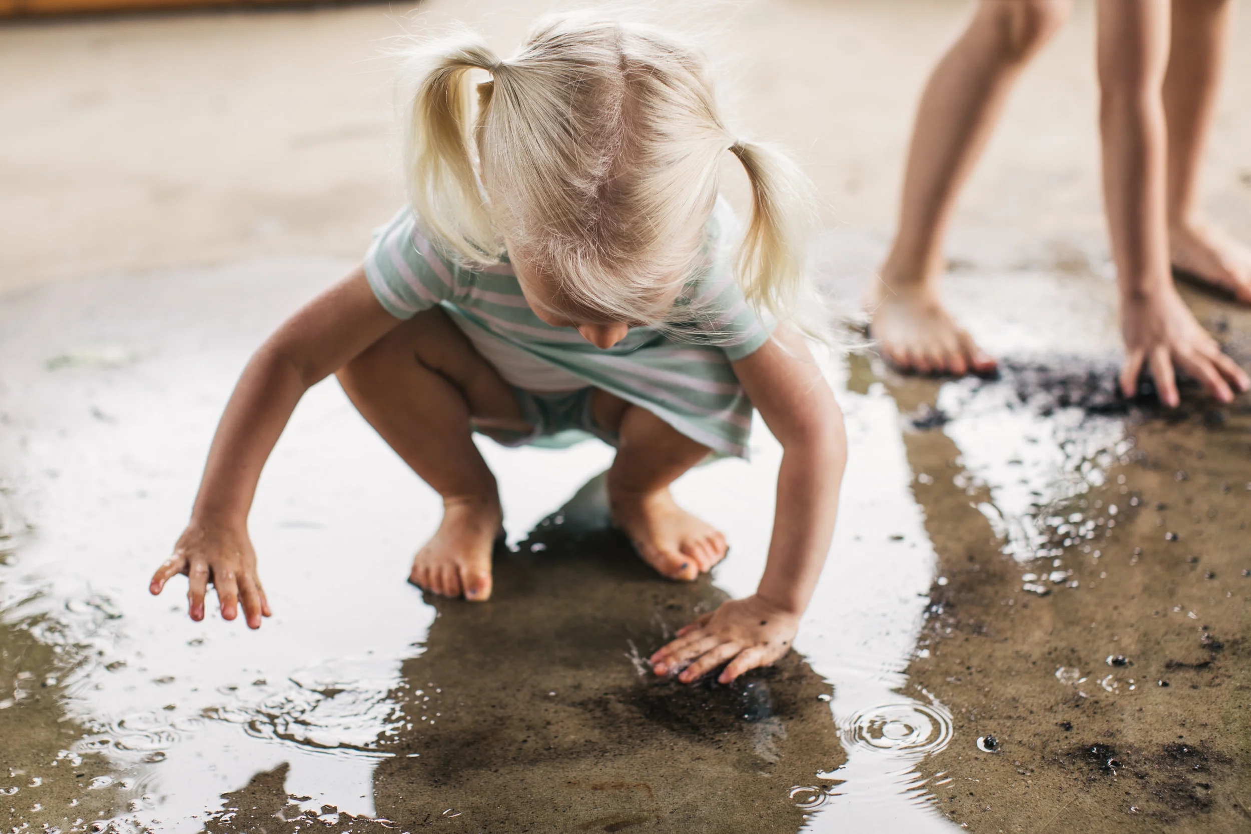 Family portrait of older sibling playing in the puddles after a rainfall outside of their beautiful Maryland home.