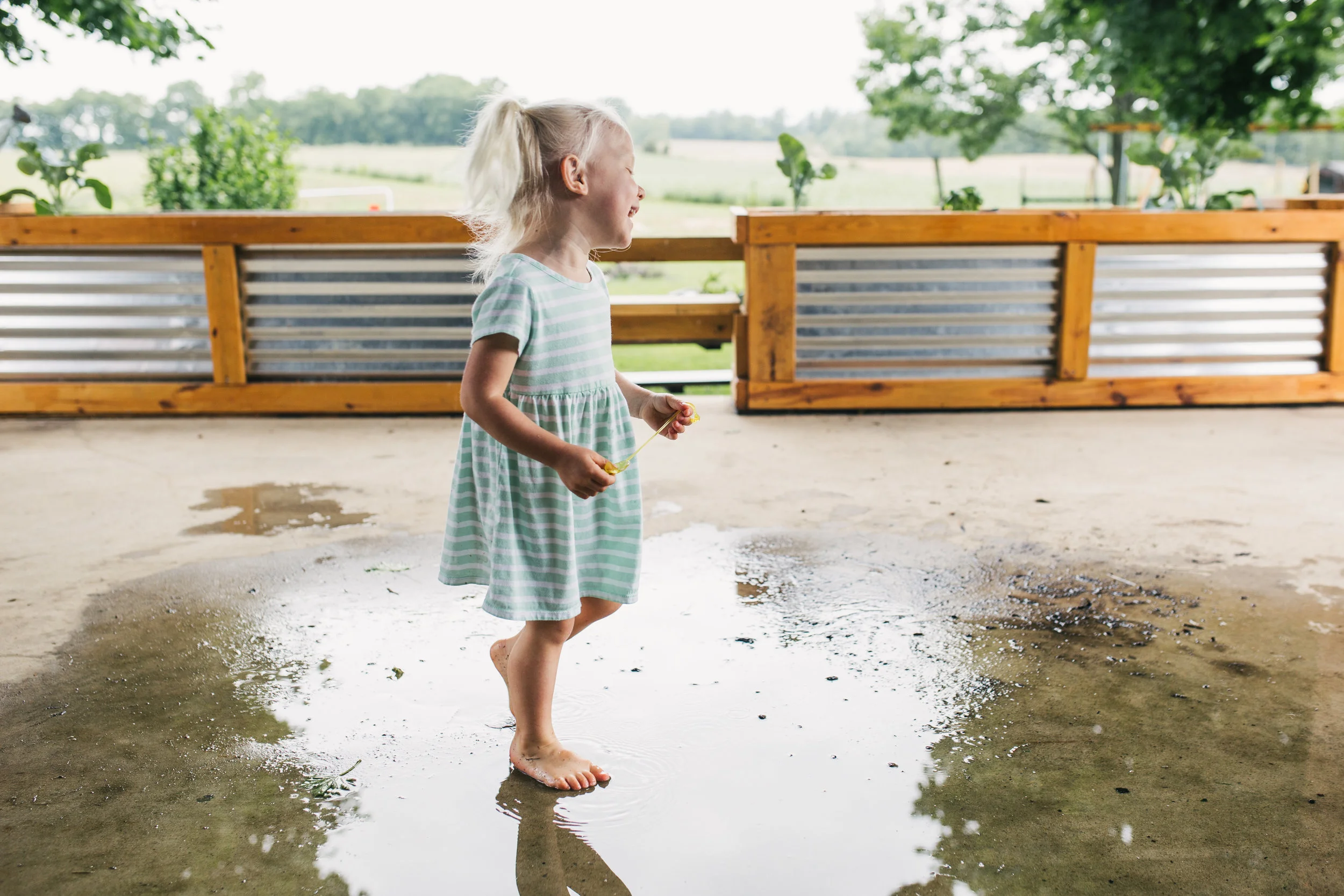 Family portrait of older sibling playing outside after a rainfall at their beautiful Maryland home.