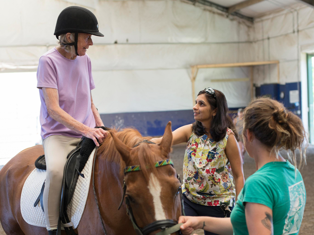 Penelope Maynard (left) is riding horses again thanks to help from Naseem Chatiwala, DPT, NCS, (center) a neuro specialist at Emerson's Center for Rehabilitative and Sports Therapies.