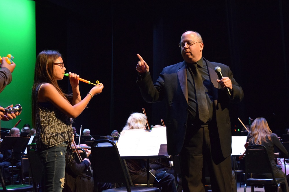 A Norwalk-La Mirada student makes her musical debut with assistance from La Mirada Symphony conductor Alan Mautner on April 19, during a pair of performances with the La Mirada Symphony by thirty NLMUSD middle school honor band musicians.