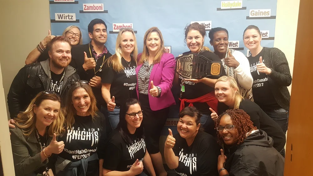 Jackson Middle School Principal Kelly Anderson, back middle left, celebrates with Paramount Superintendent Dr. Ruth Pérez, back middle right, and Jackson faculty and staff after winning the inaugural March Madness fundraiser, which raised over $95,000 for the Paramount Educational Partnership.
