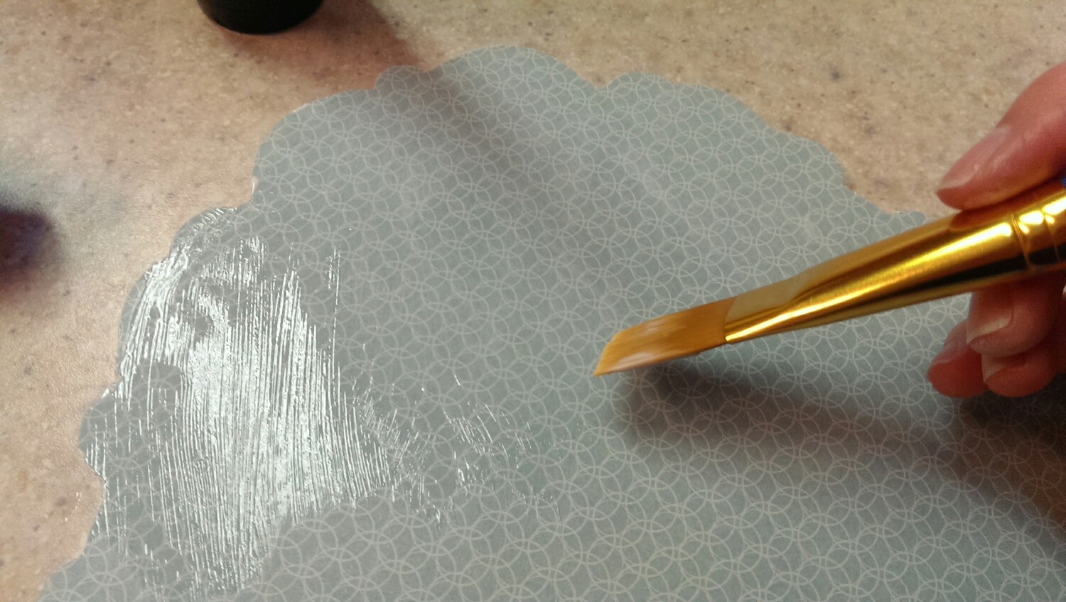 Coating the scrapbook paper with Mod Podge.