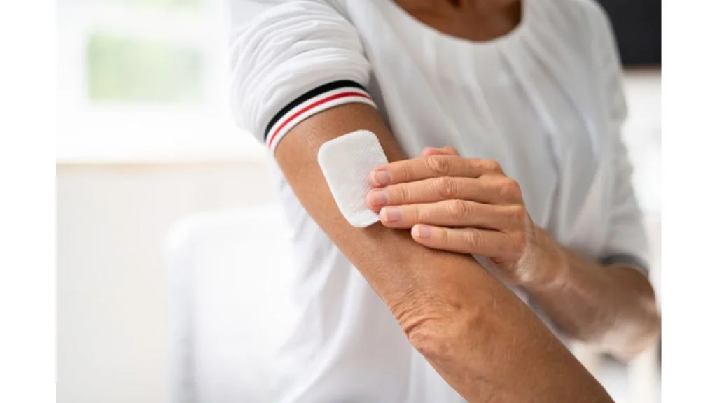 A person applying a bandage to their forearm.