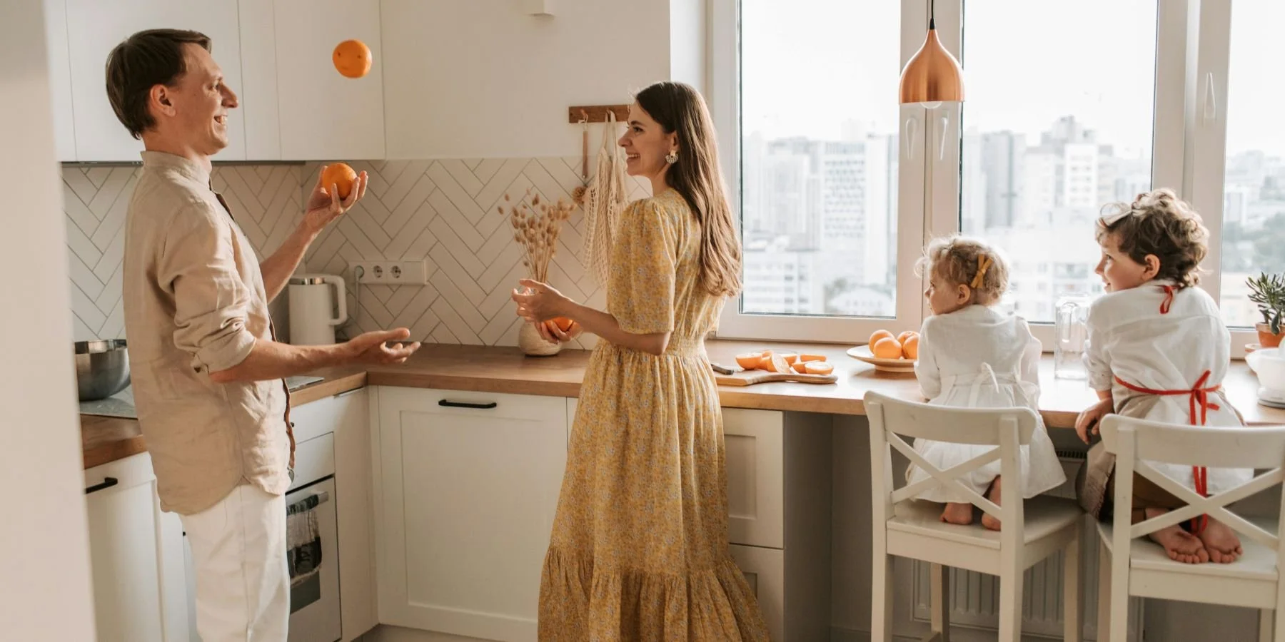 Dad juggling oranges and mom and the kids laughing