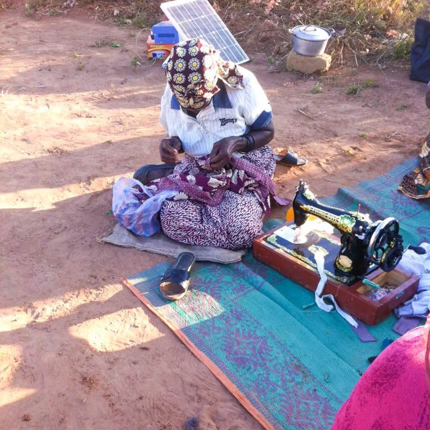 The oldest woman of the village, who the ladies refer to as "Sweet Sixteen," hard at work using the manual hand sewing machine.